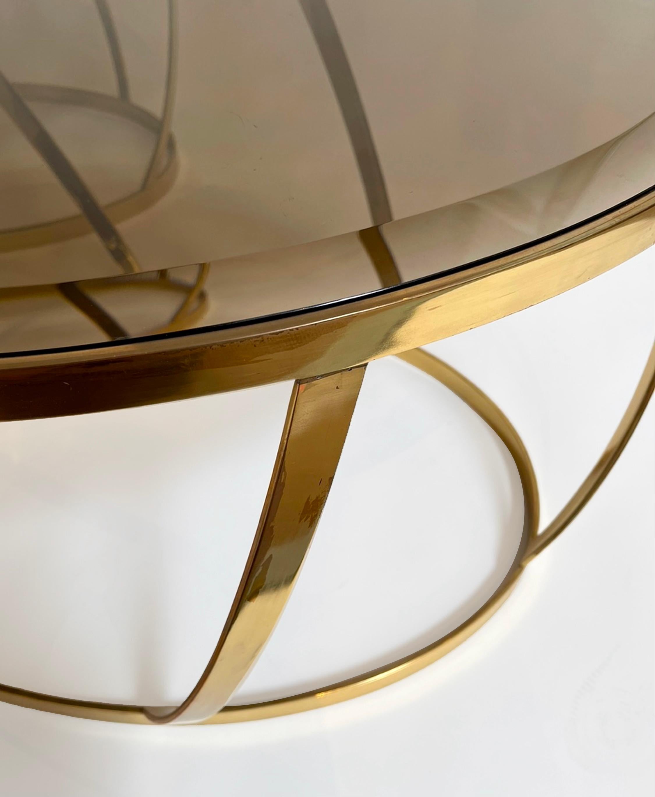Polished and glamorous oval side tables by Karl Springer. Made of solid brass and beveled, smokey brown glass. Removable glass for easy transport. Sold as a set. This is an authentic, original Karl Springer design. Ready for use.
 