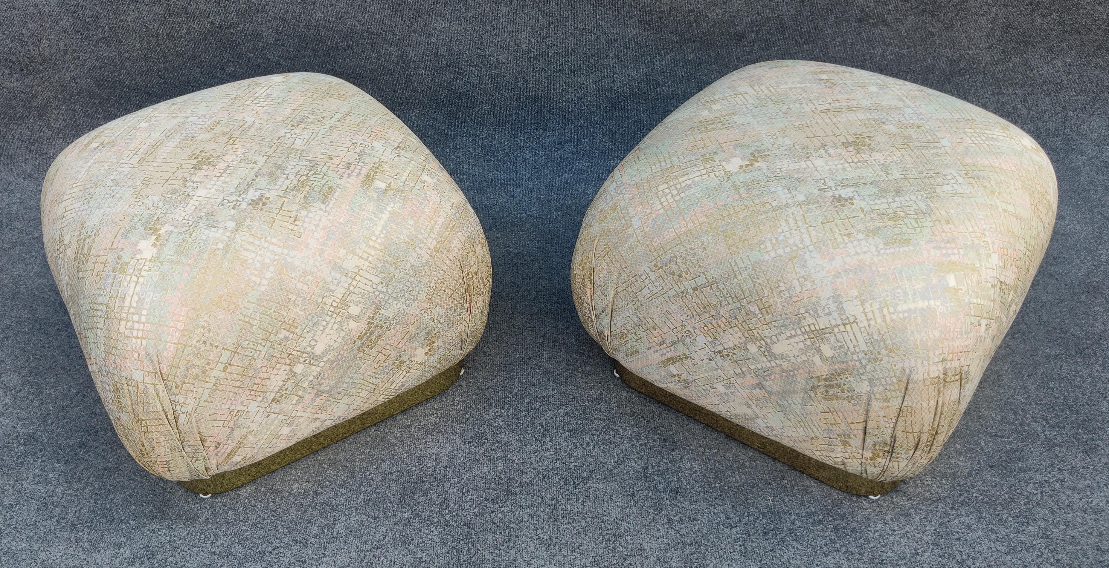 This pair of poufs or ottomans were made in the 1980s after the design was made iconic by Karl Springer. On a base of brass plated sheet metal over a wooden frame, this pair is upholstered in a pleasing tesselated, almost floral pattern. They are
