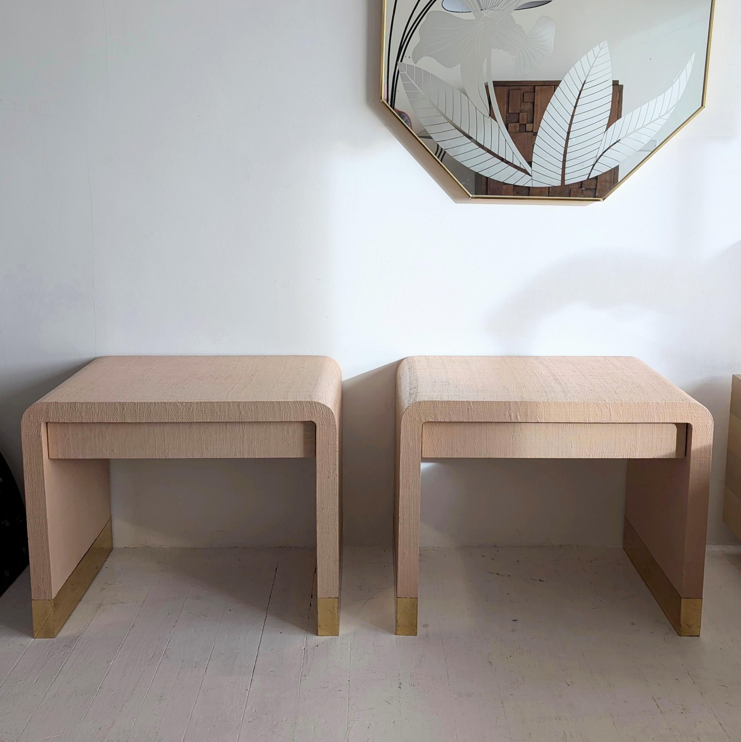 Pair of large Karl Springer-style waterfall bedside tables, USA 1980s. Peach lacquered grasscloth with brass bases. One wood-lined drawer in each. Would also look great as side tables in a lounge setting.