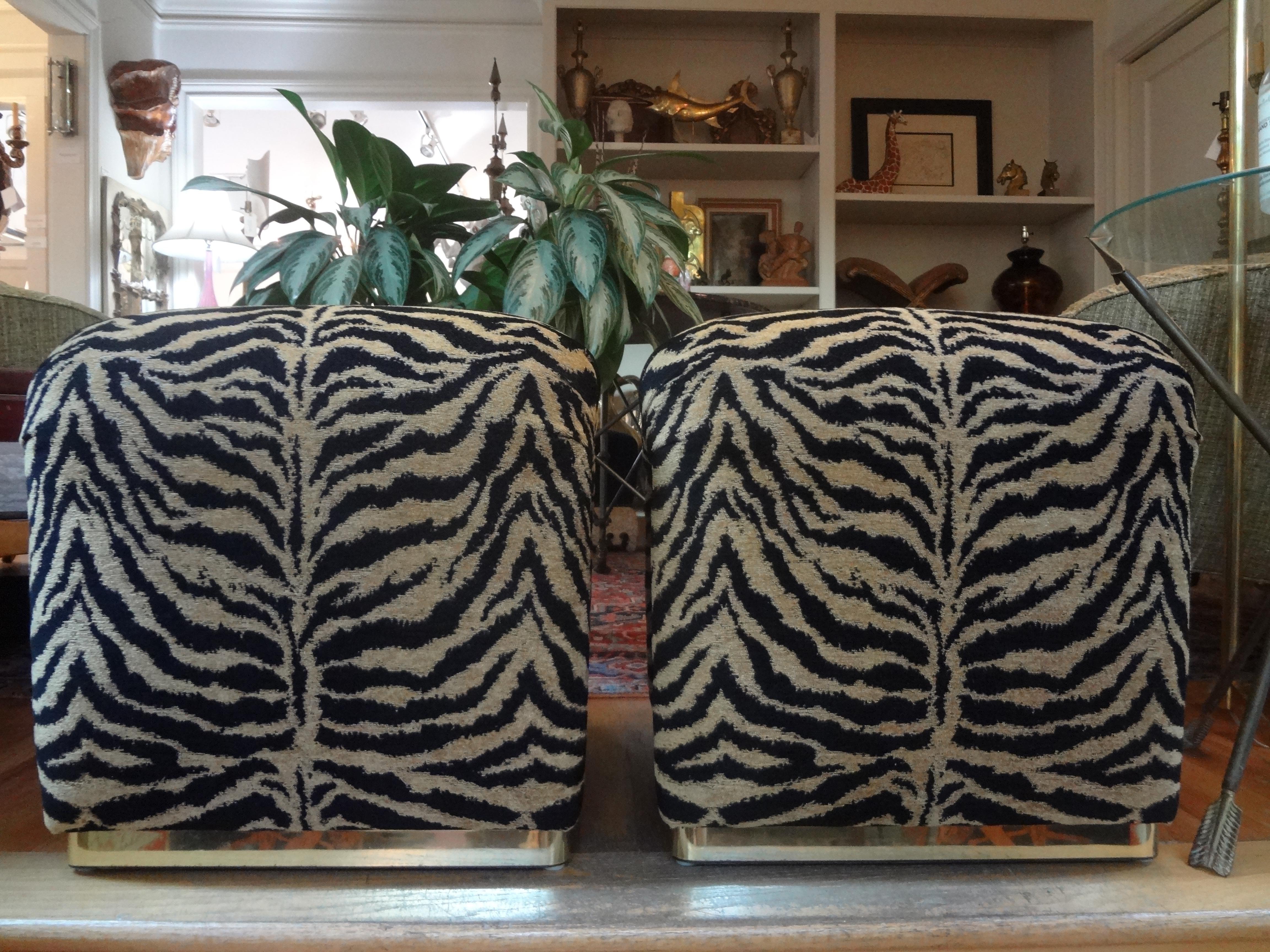 Stunning pair of Karl Springer style waterfall benches, ottomans or poofs with brass bases. These beautiful Hollywood Regency benches have been professionally upholstered in black and gold tiger print chenille. These mid-century stools are very