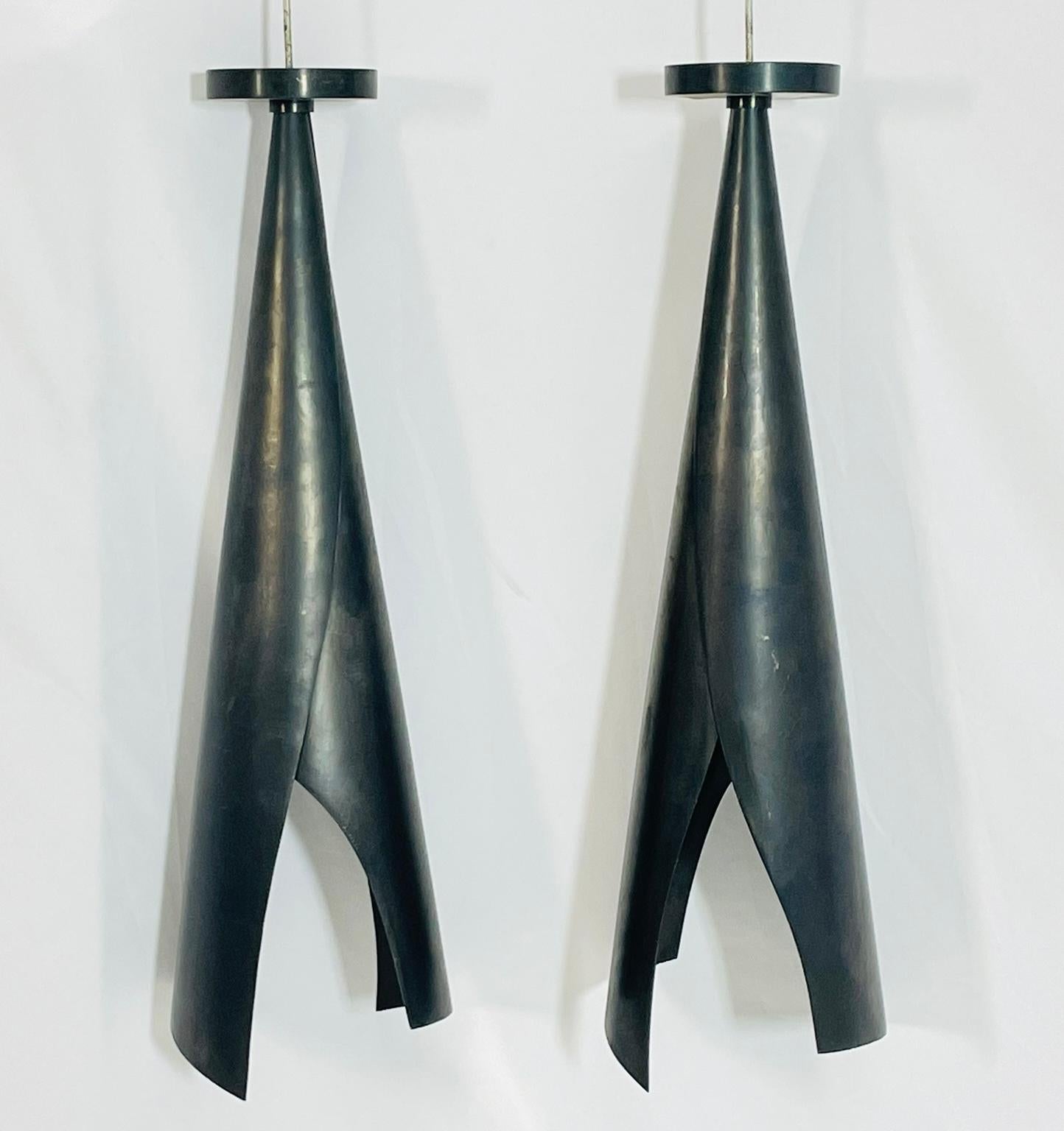 Remarquable paire de lampes suspendues sculpturales conçues par Kelly Wearstler pour Visual Comfort, présentant une silhouette audacieuse et contemporaine en bronze foncé. Ces pendentifs spectaculaires sont fabriqués dans une forme conique effilée