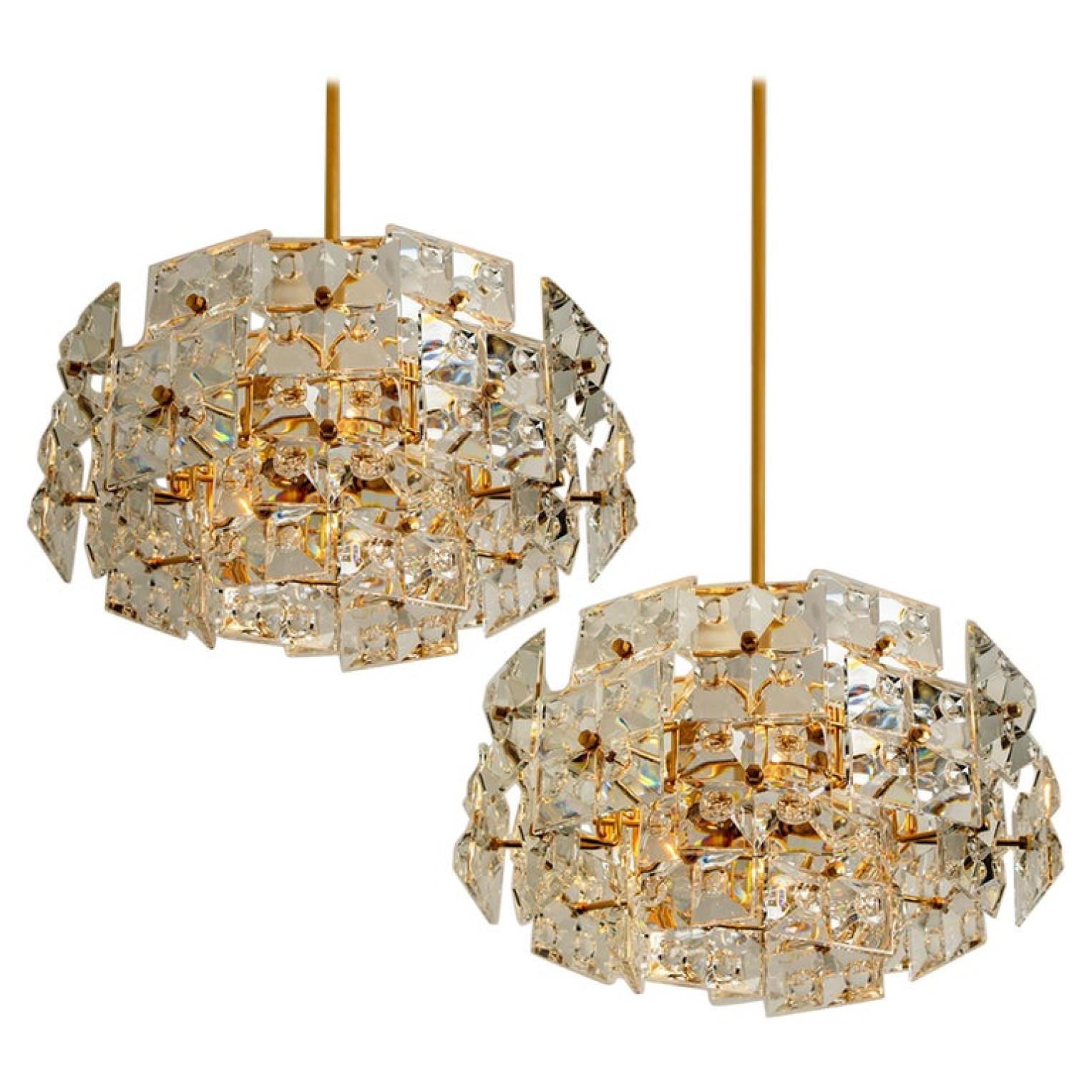 A very exclusive and high quality chandelier by Kinkeldey, Germany, manufactured in midcentury, circa 1970 (late 1960s or early 1970s). It is made of a gilded / gilt frame which holds large cut crystal glass with the dimensions of 4 x 4 in. (10 x 10