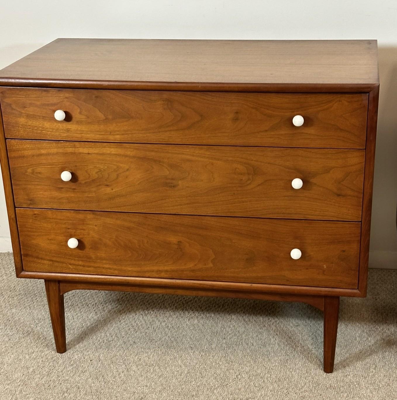Pair of lovely Kipp Stewart Declaration by Drexel 3-drawer walnut bachelor chests from the 1960's. Drawers feature round white porcelain pulls and dovetail construction. Sits on a base with round tapered legs. 36