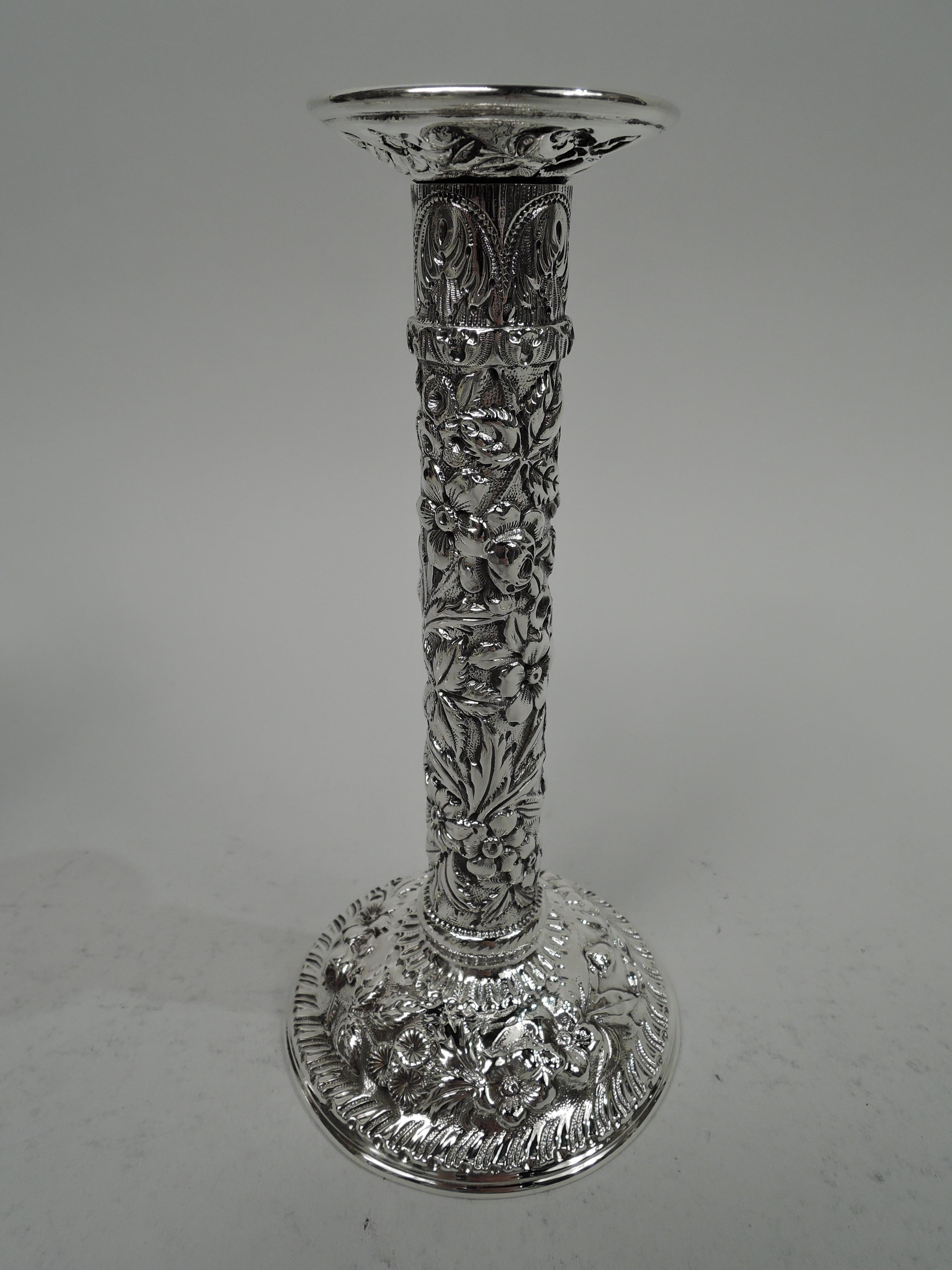 Pair of Edwardian Classical sterling silver candlesticks. Made by S. Kirk & Son Co. in Baltimore, ca 1910. Knopped and banded columnar shaft on domed foot. Dense floral repousse with gadrooned, pointille, and leaf-and-dart borders. Fully marked