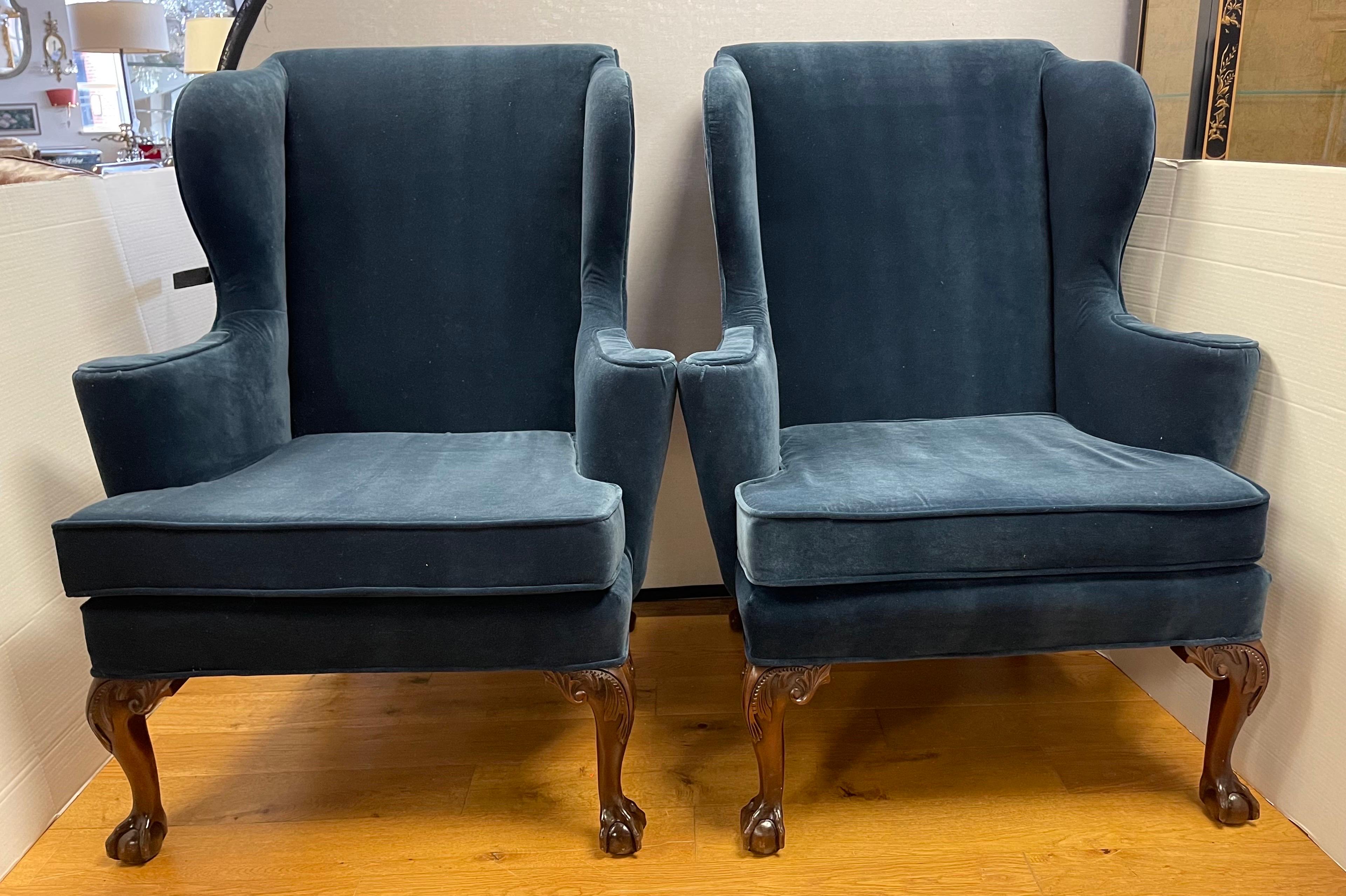 A gorgeous pair of matching Kittinger Georgian wingback chairs with newly upholstered navy blue Donghia fabric. The chairs sit on intricately carved mahogany ball and claw feet. Nothing short of magnificent. All fabric and padding textile have been