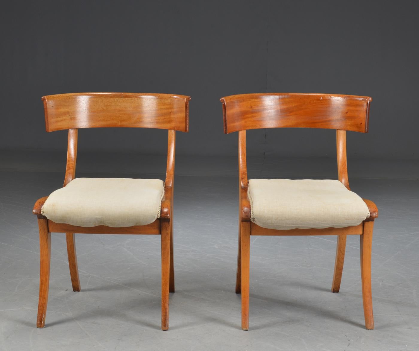 Pair Klismo chairs with curved mahogany lacquered frame. Seats upholstered in light beige upholstery fabric.
