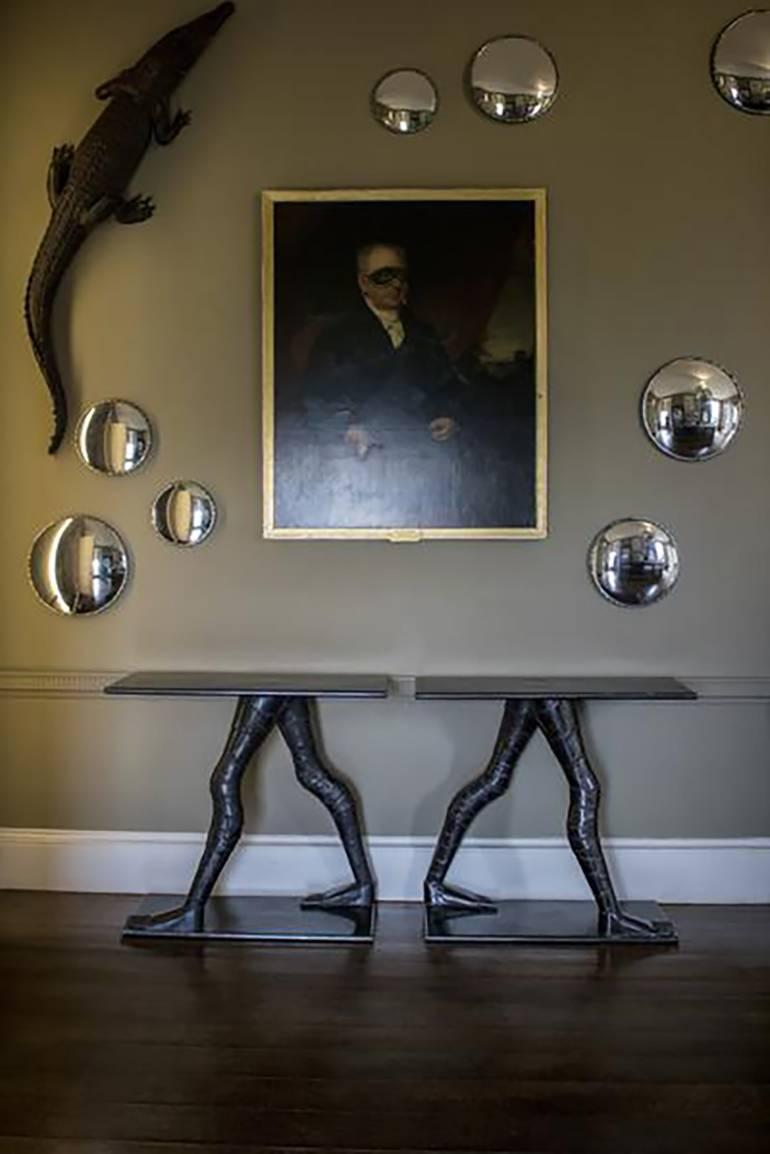A pair of console tables in welded iron, raised on stylised leg supports.