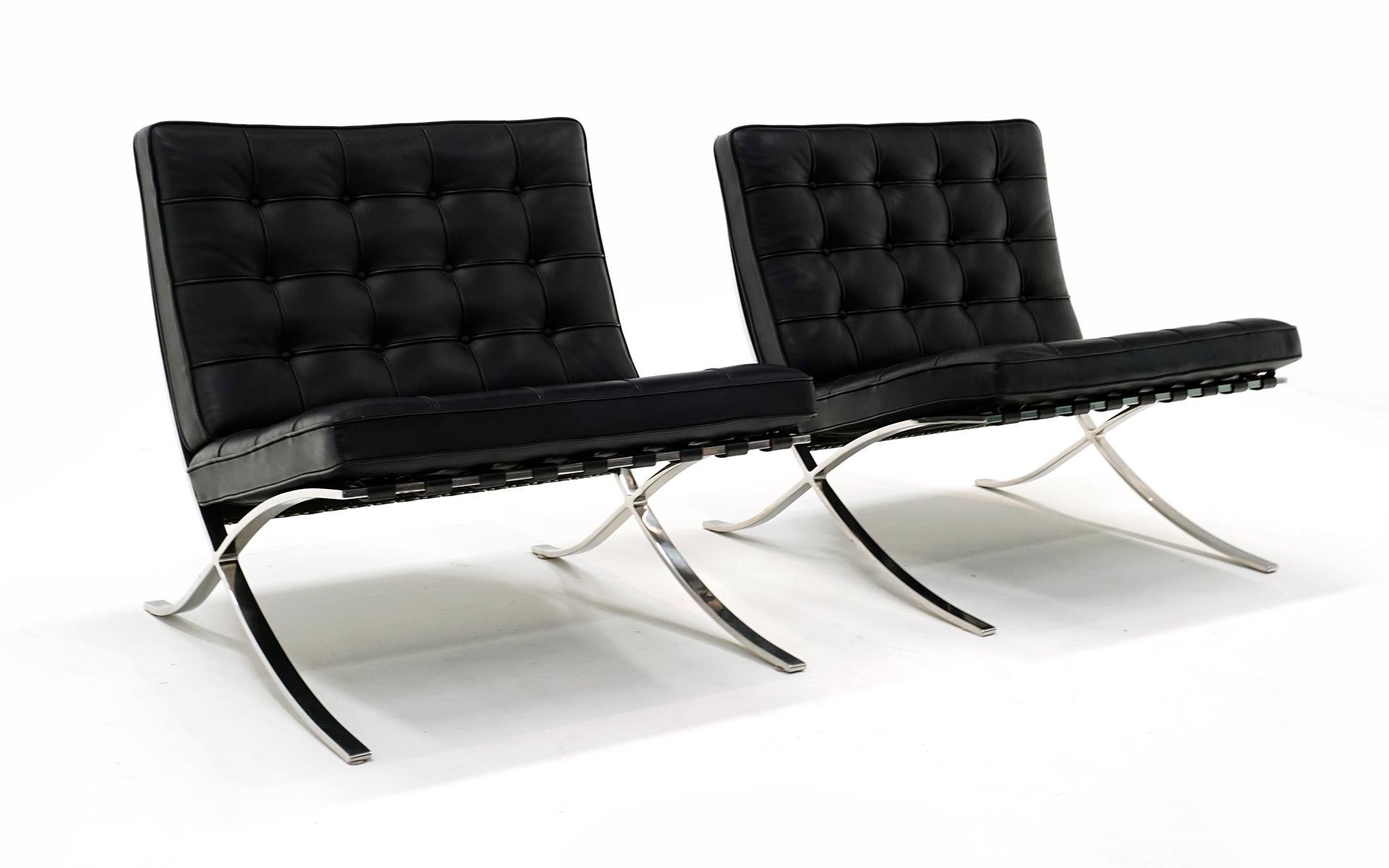Pair / Two black leather and stainless steel Barcelona Chairs designed by Ludwig Mies van der Rohe and produced by Knoll. Each example is signed with the Knoll Studio markings. Very few signs of use. Light scratches to the tops of the stainless