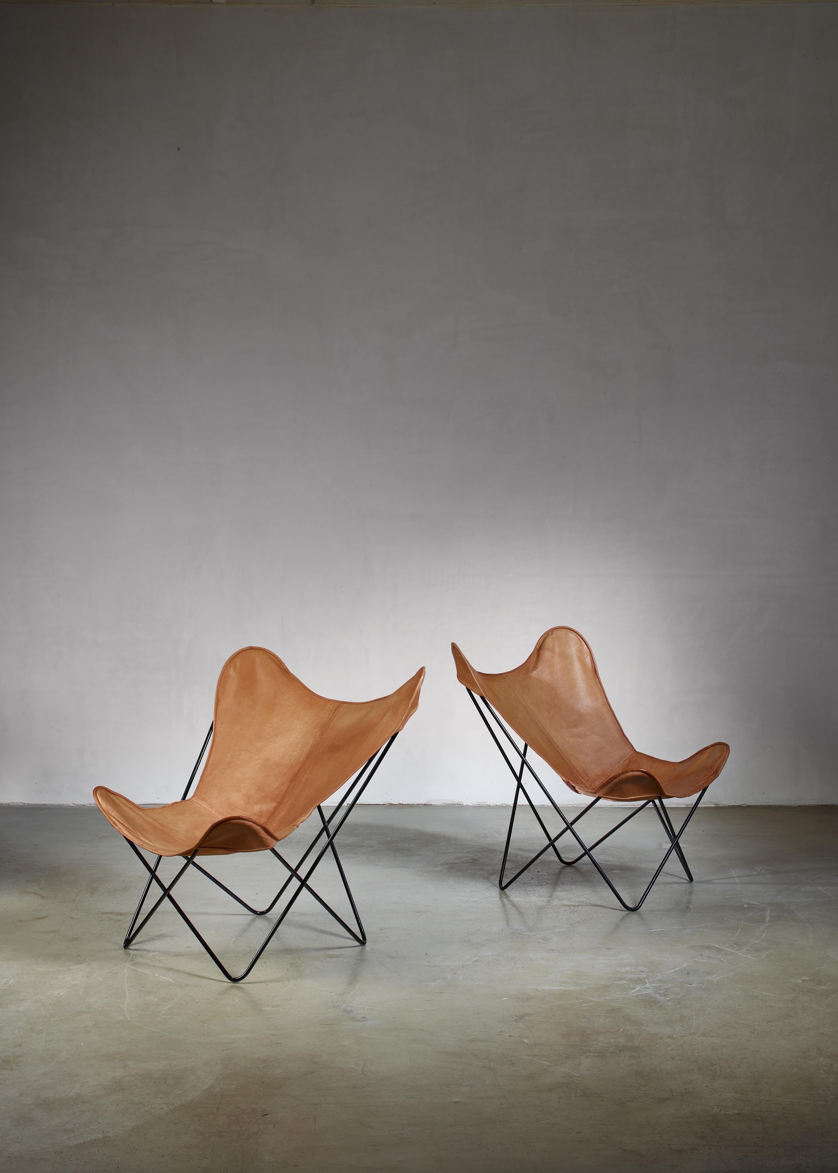 A pair of Knoll butterfly chairs, designed in 1938 by Antonio Bonet, Juan Kurchan and Jorge Ferrari-Hardoy. The chairs have a thin, black lacquered metal frame with a tan leather sling seating with a beautiful mild patina.

Both chairs are in