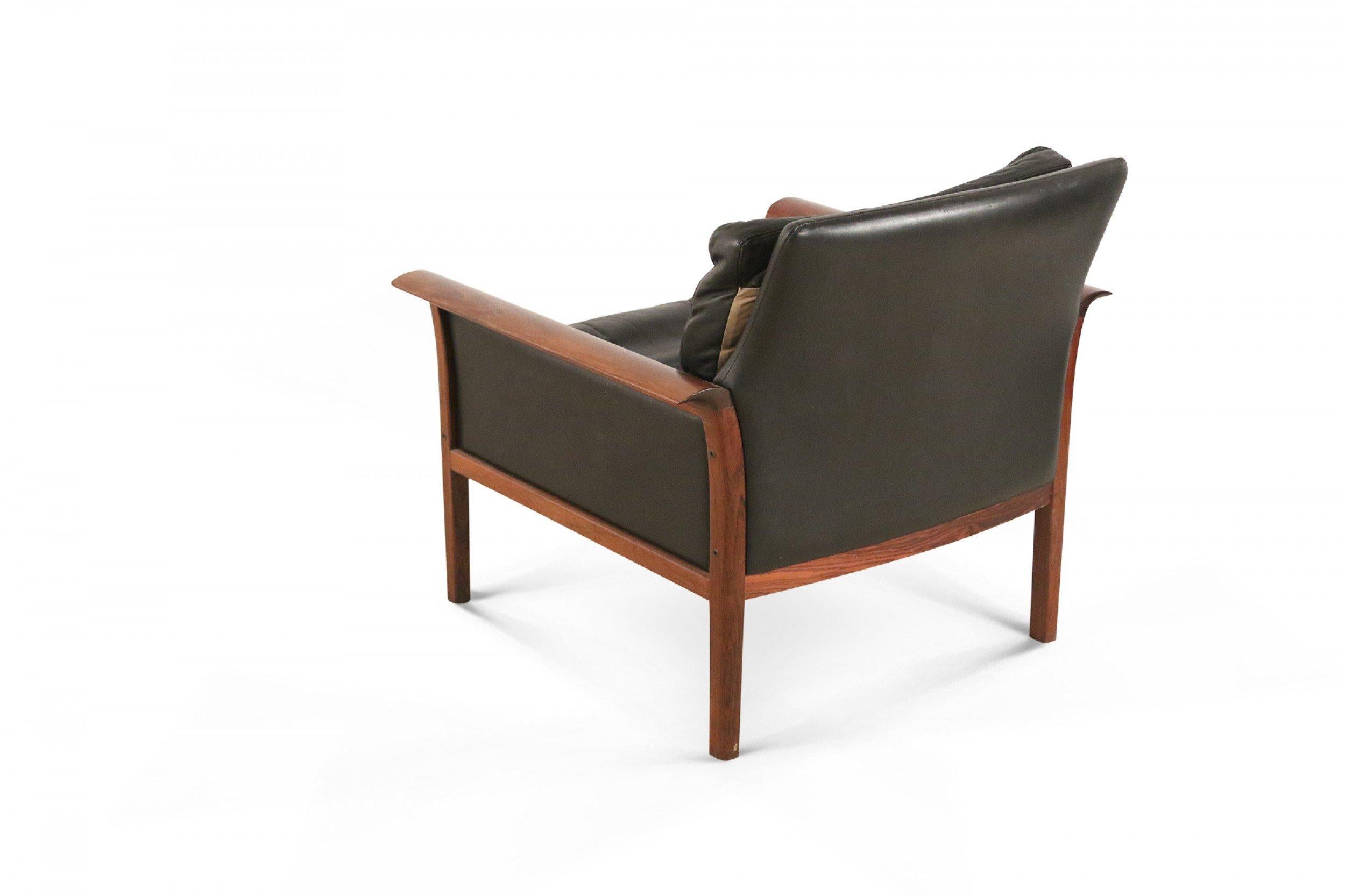 Pair of mid-century norwegian armchairs with rosewood frames and armrests and black leather upholstery. (Knut Saeter for Vatner Mobler) (priced as pair).
 