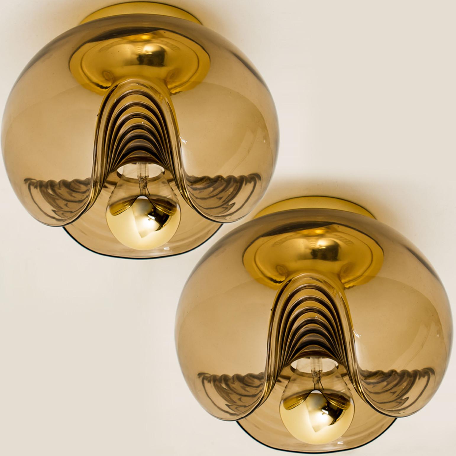 Midcentury flush mounts, wall lights or sconces designed by Koch & Lowy for Peill & Putzler in the 1970s. Featuring a smoked glass globe shade with a waved/ribbed molded bubble form. Casting a stunning rippled light across a wall or ceiling. The