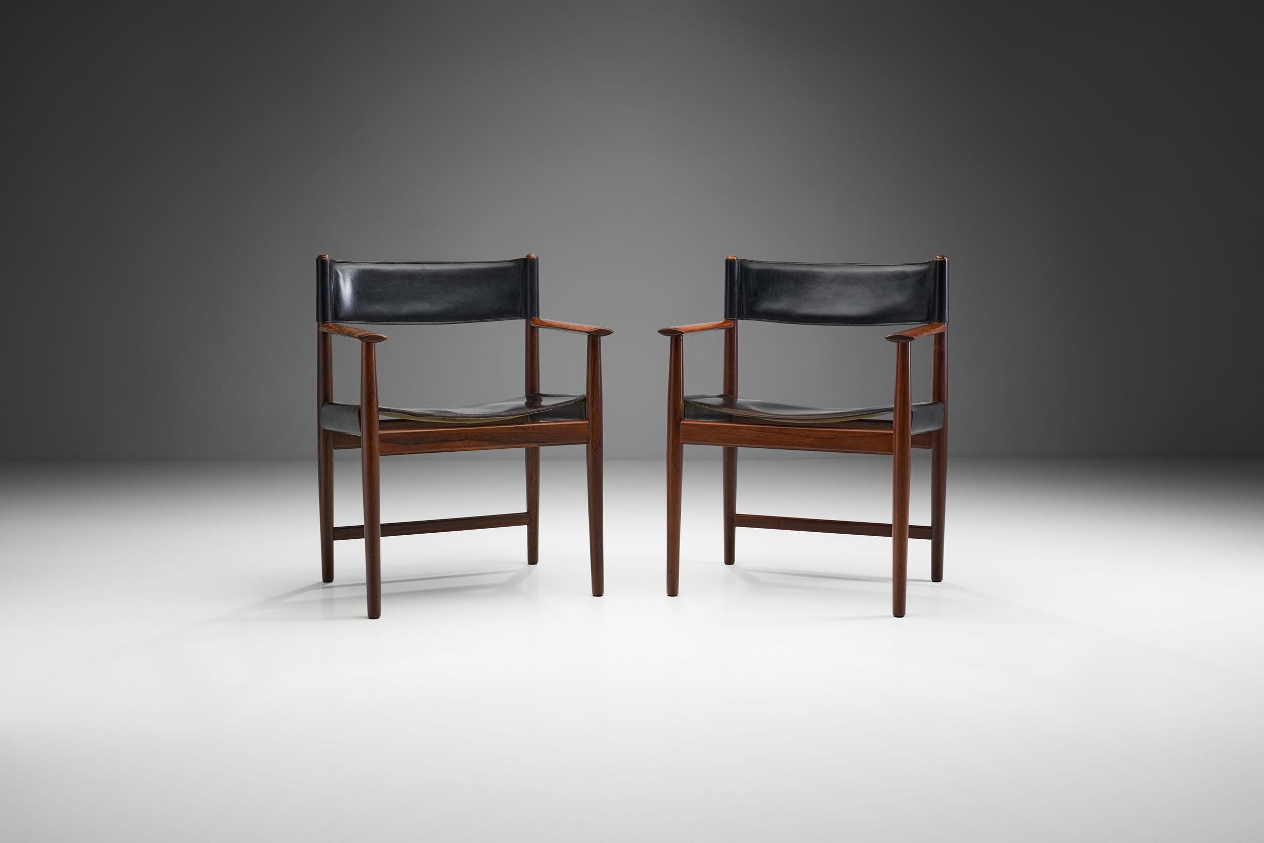 This pair of dining chairs by Danish designer Kurt Østervig is a beautiful example of simple, refined midcentury Danish design.

The black leather chairs are made of beautifully aged wood, with a dark color. The combination of the deep color of