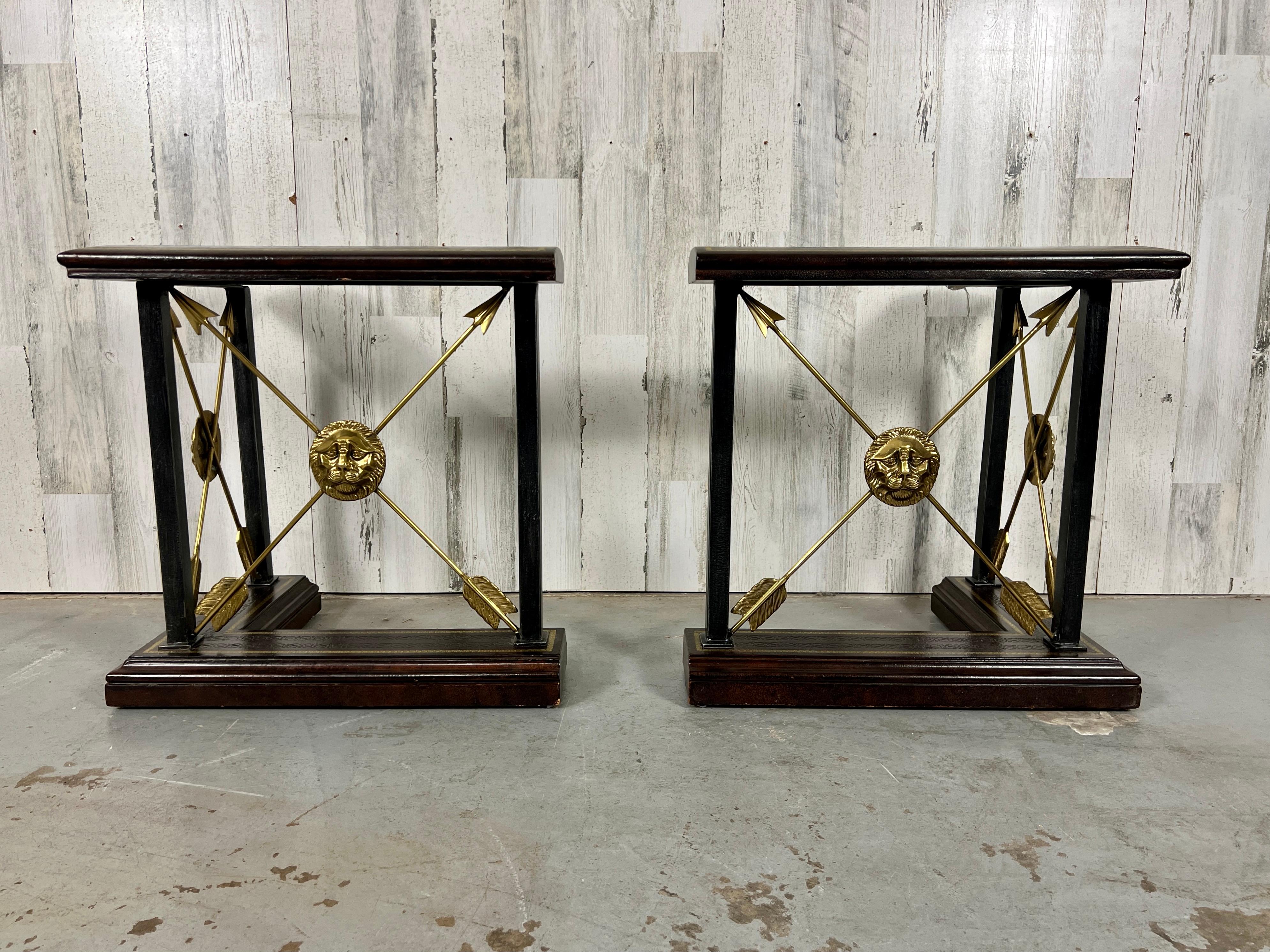 A pair of L-shaped fireplace fenders. Leather lined tops and bottoms with embossed gilt inlays. The bases having crossed brass arrows with lion mask faces. 
Very comfortable for warming yourself by the fire.
