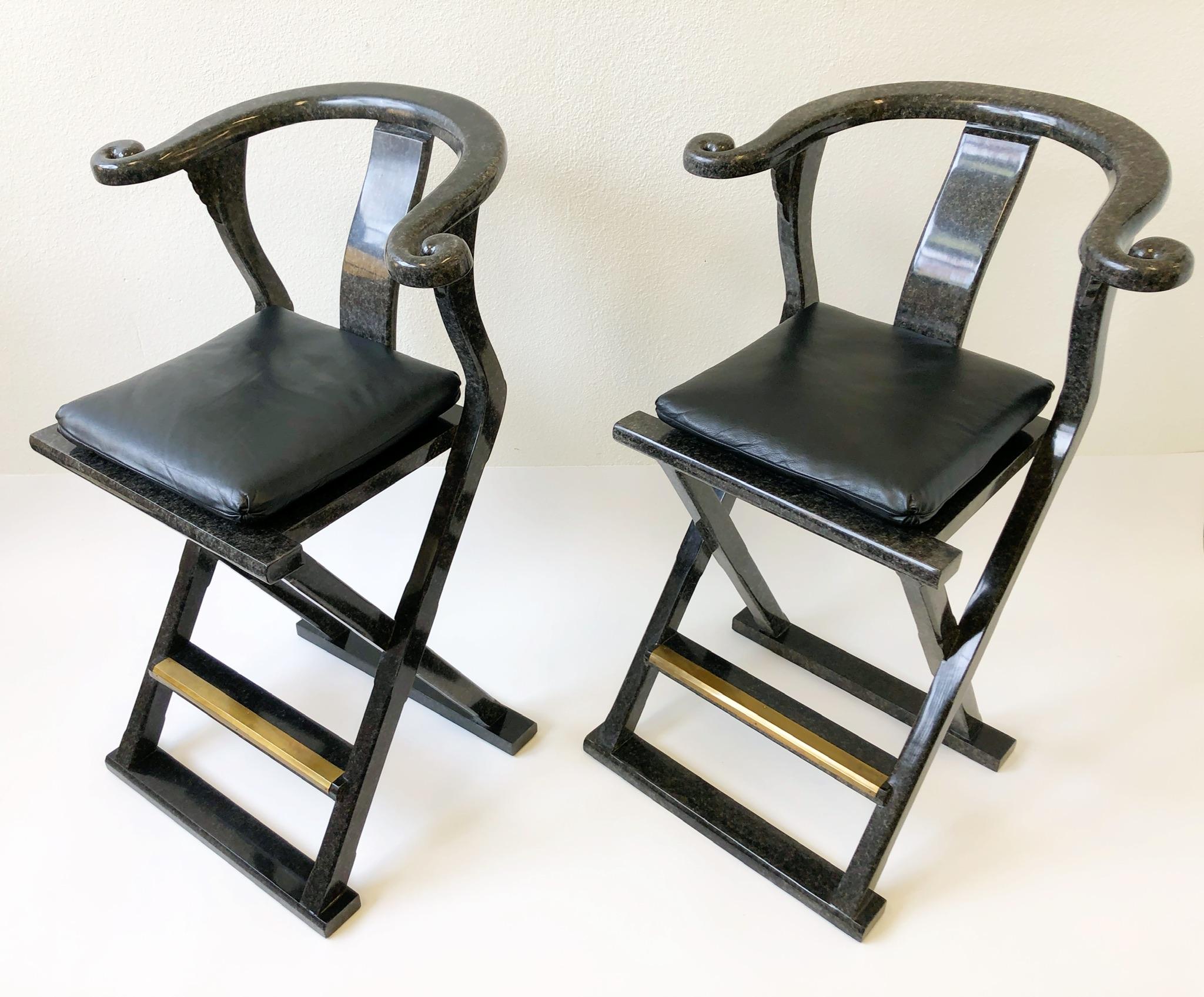 A glamorous pair of faux granite lacquered Asian Style barstools design by Marge Carson in the 1980s. The stools are constructed of wood that’s painted in black and gray faux granite lacquered finish. The seat is black leather and the footrest is