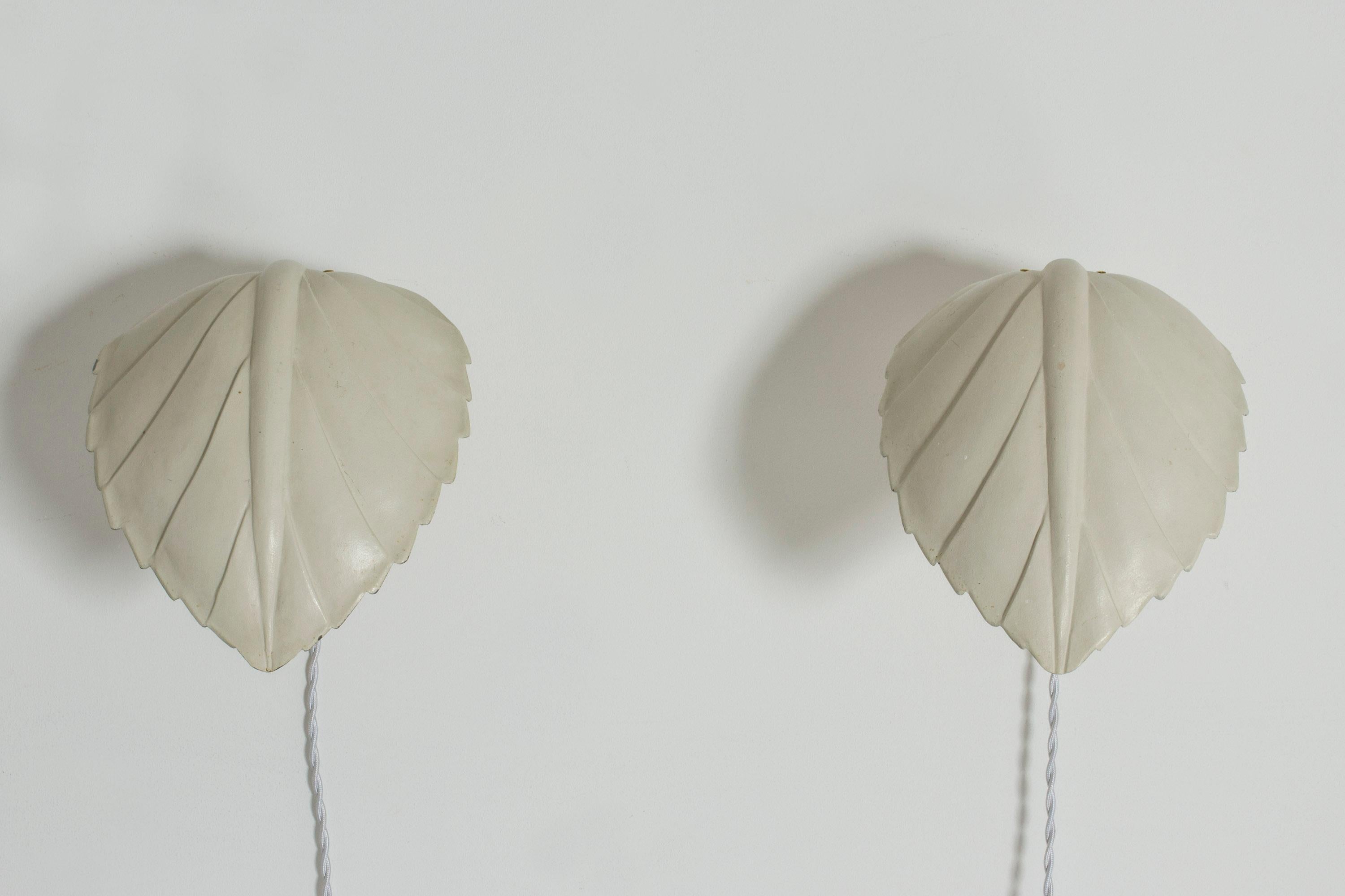 Pair of beautiful wall lights by Hans Bergström, in the form of stylized leaves. Sconces lacquered eggshell white with brass details.