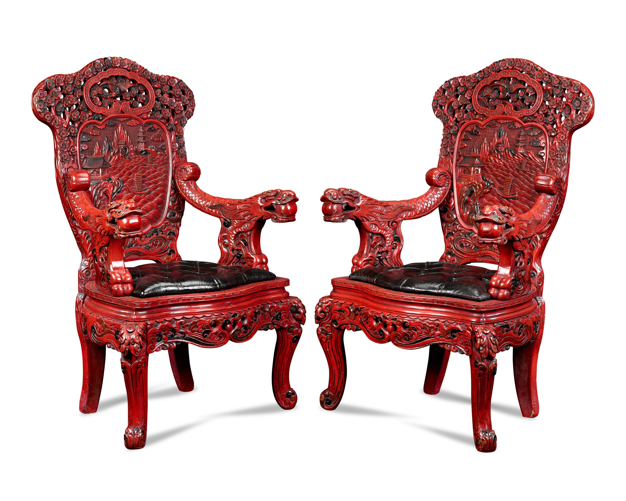 These breathtaking Chinese throne chairs hailing from the late Qing dynasty are each elaborately carved of wood and covered in sumptuous red and black lacquer. Every inch of the pair is carved with Chinese motifs including scrollwork and cherry