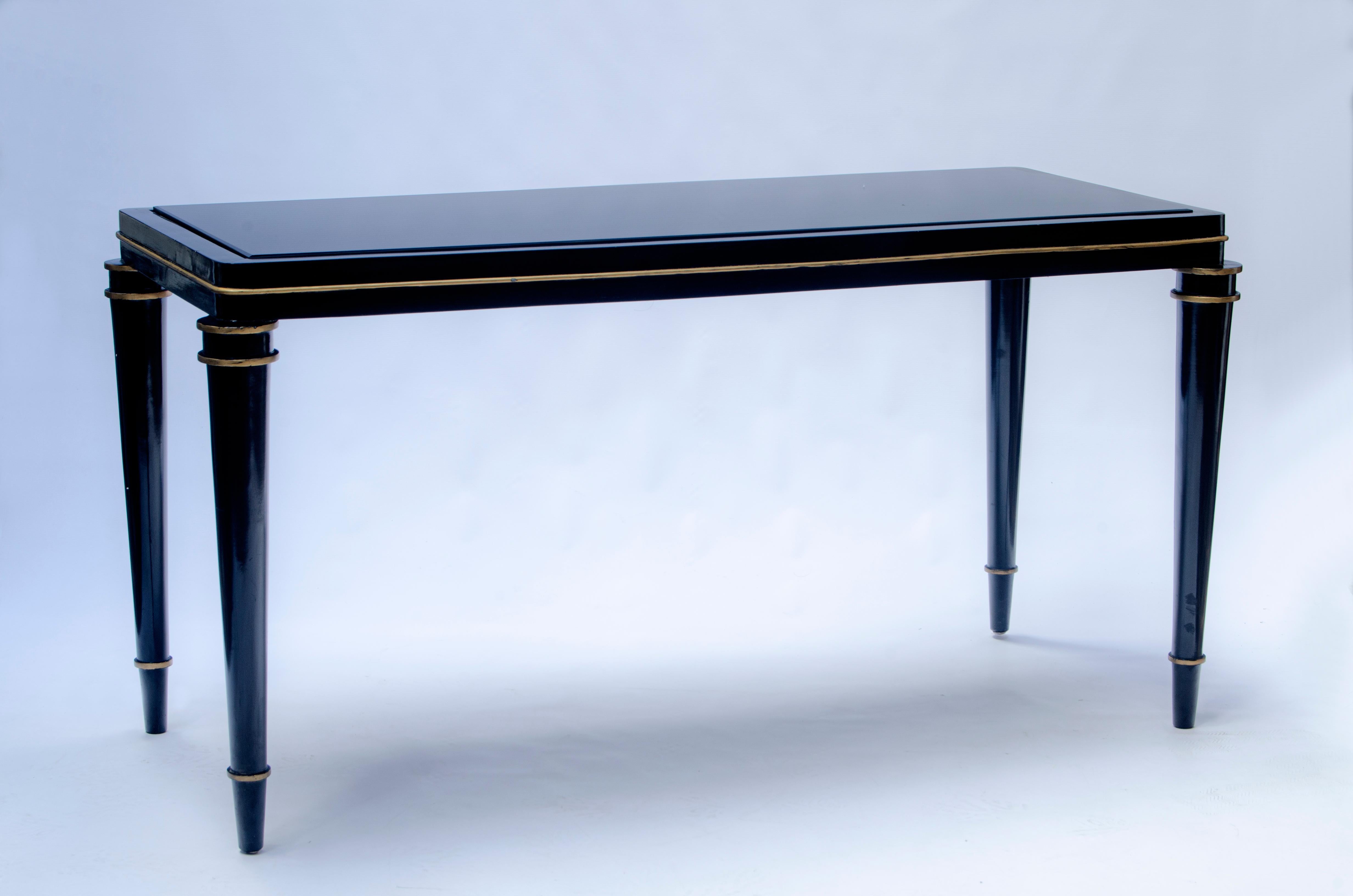 Coppia di consolle in legno laccato nero, con dettagli dorati e piani in vetro nero, della Maison Jansen. (1880-1989).

Francia, CIRCA 1920.