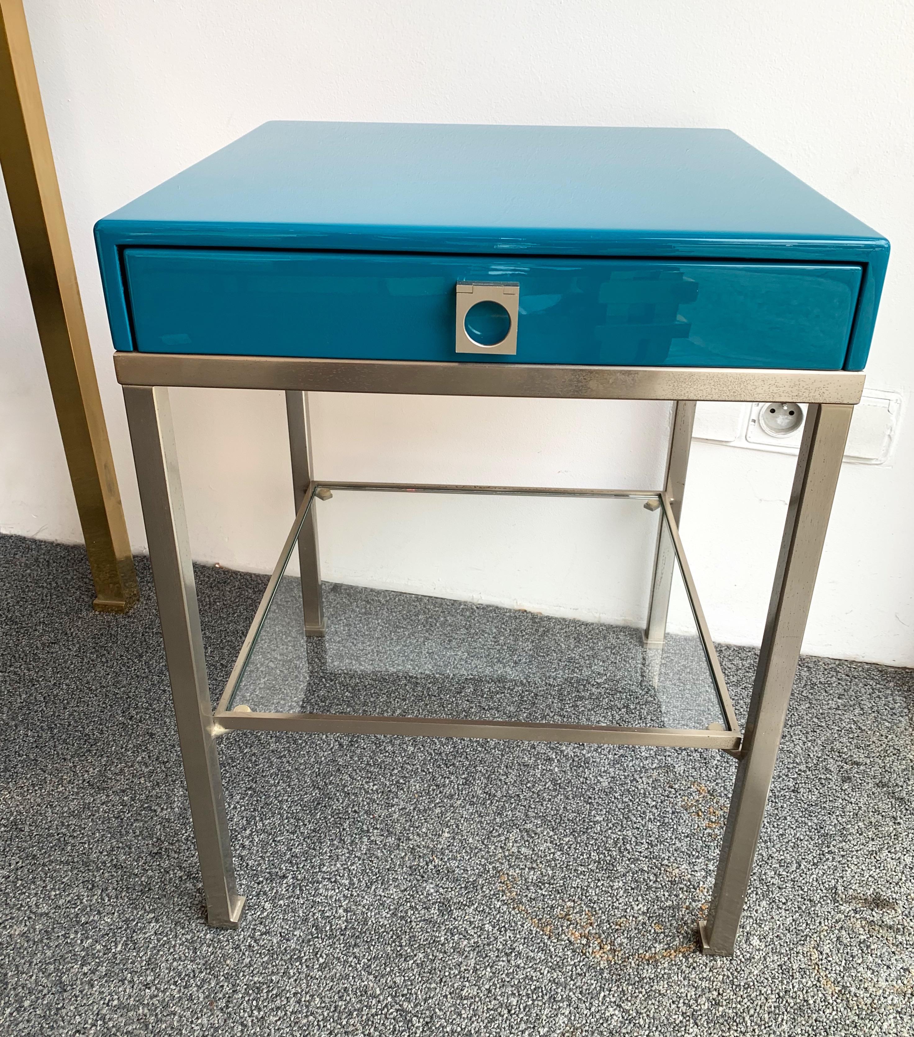 Pair of blue turquoise lacquered side end tables or nightstands by Guy Lefèvre. A part of his production was diffused by the Maison Jansen in Paris, nickeled brass feet, glass shelf. Famous design like Jean Claude Mahey, Willy Rizzo, Mario Sabot.