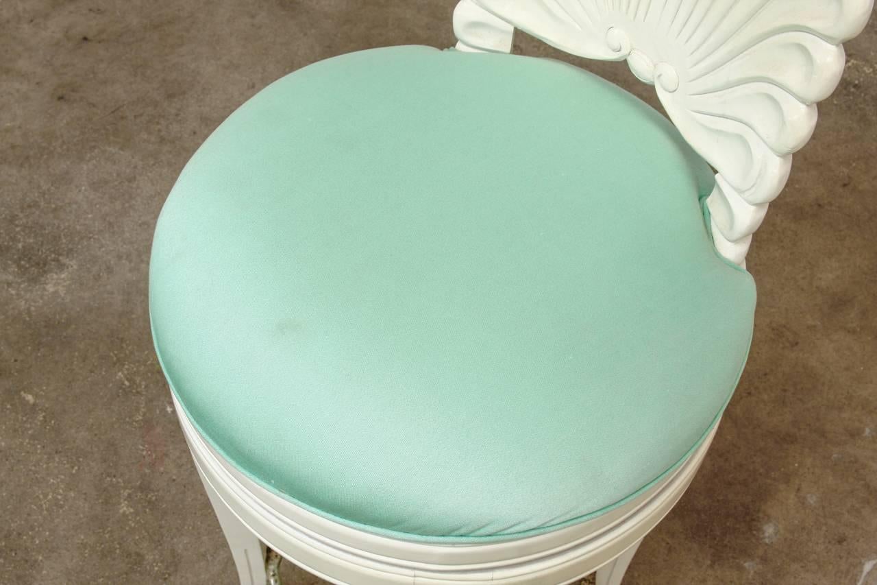 Pair of Hollywood Regency style Venetian grotto shell-back barstools featuring a Florida Regency style white lacquered finish. Classic carved shell back motif and vintage sea foam green upholstery. Measure: Seat height: 30