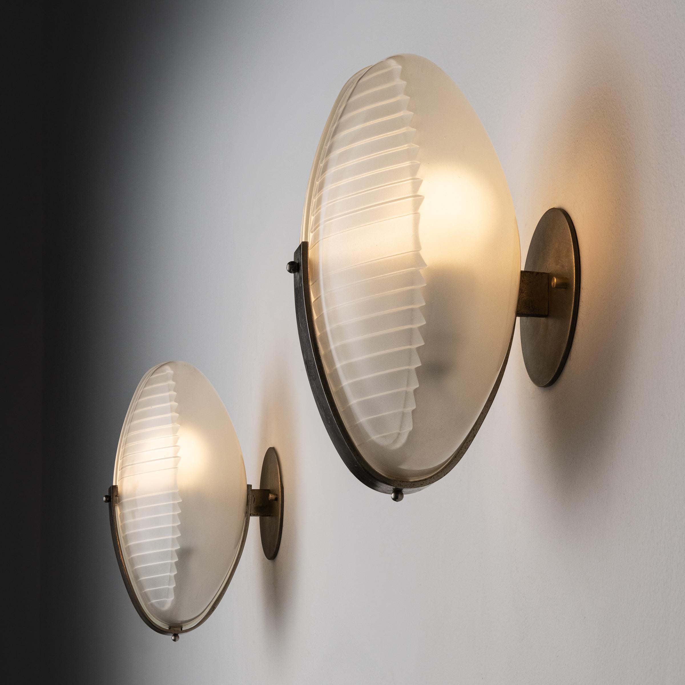 Pair of Lambda sconces by Vico Magistretti. Designed and manufactured in Italy, circa 1950's. Glass, brass, custom brass backplates. Wired for U.S. standards. We recommend one E14 Candelabra 40w maximum bulb per sconce. Bulbs not included.