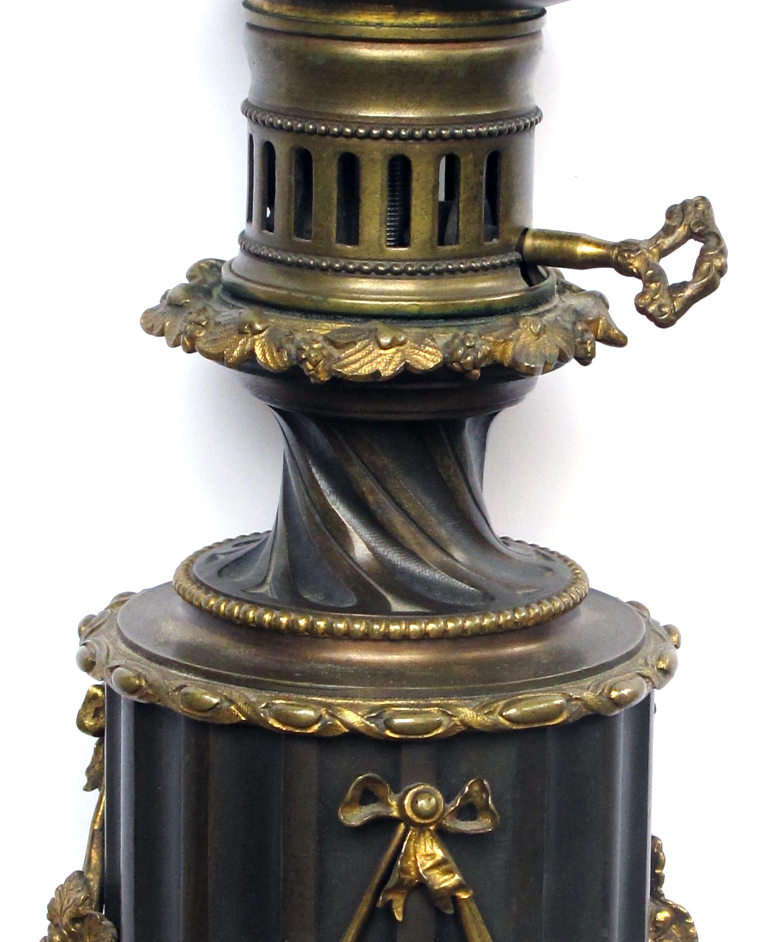 A rare and good quality pair of Lampe a Moderateur, Paris Louis Philippe bronze oil lamps now electrified; each with flared neck above a fluted cylindrical body adorned with finely detailed gilt-bronze grapevine swags; all raised on a gilt-wood