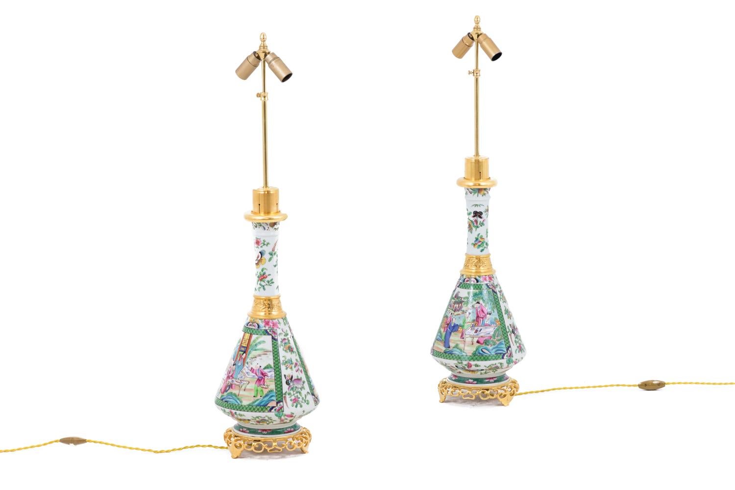 Pair of conical shape lamps in Canton porcelain and gilt bronze with a narrow neck. Decor of flowers and butterflies in pink and green tones on a white background and two large cartouches with green edges figuring palace scenes.
Chiseled and gilt