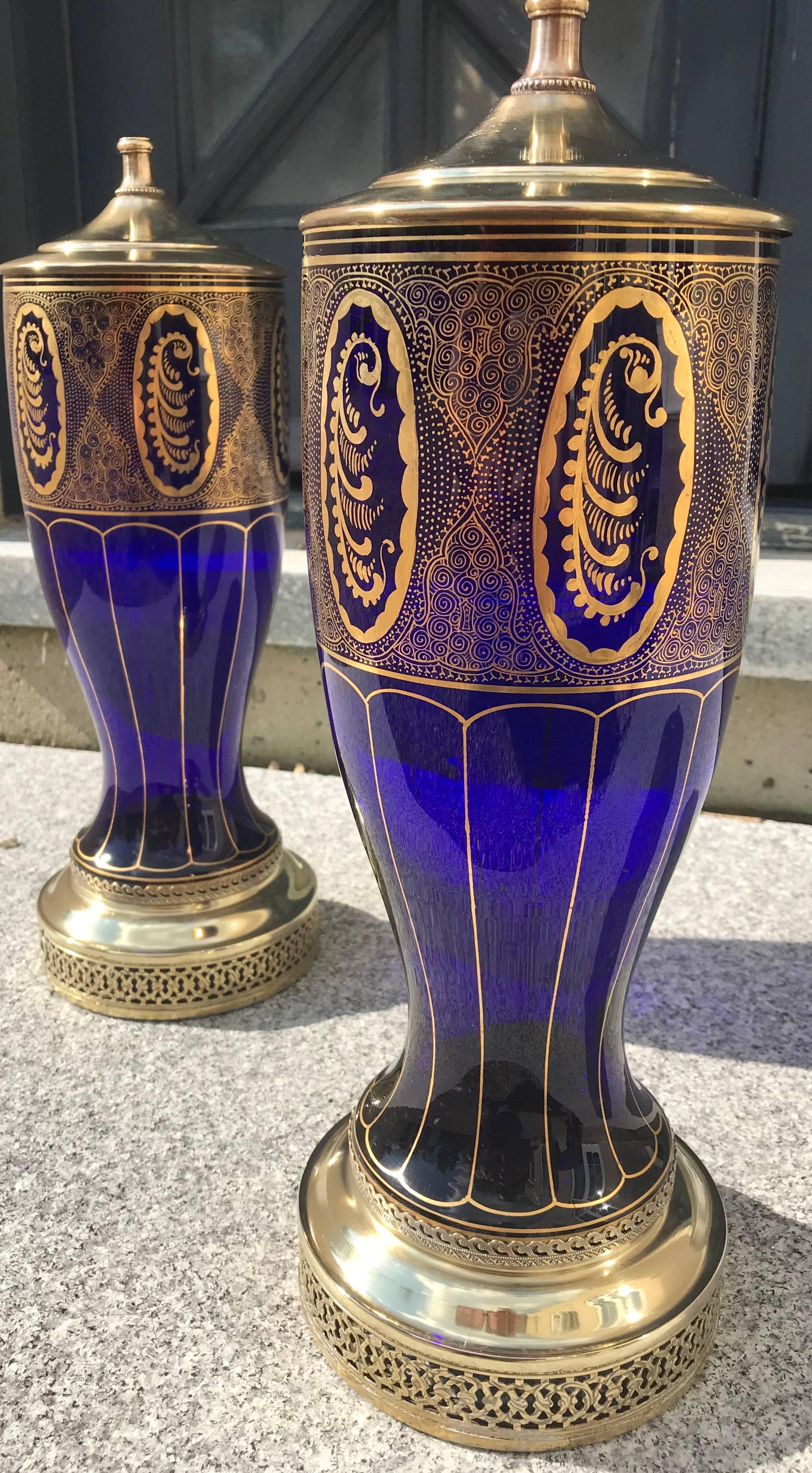 This elegant pair of handblown cobalt blue glass vases were converted into lamps in the 1930s. The gold patterns are hand applied in 24-karat gold. The lamps with tops measure 29