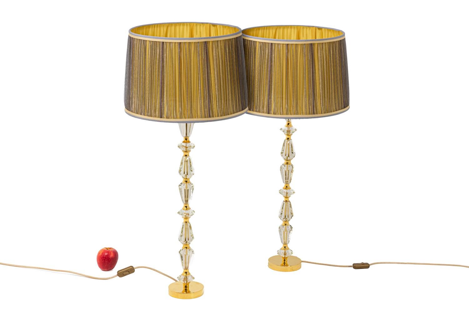 Pair of cylindric lamps composed by a row of conic elements in faceted glass separated by rings in gilt brass. Frame standing on a circular base in gilt bronze.

French work realized in the 1940s.

New and functional electric system.

!The price