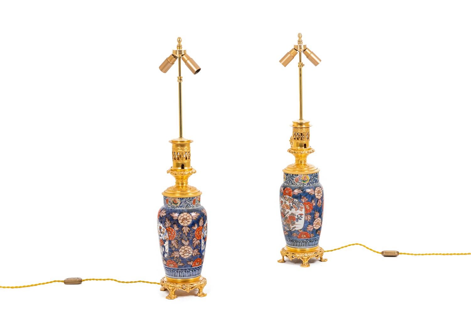 Paar Lampen aus Imari-Porzellan mit Blumendekor, verziert mit dekorativer Bronze, eiförmig mit Hals. Rahmen aus gemeißelter und vergoldeter Bronze auf einem runden Vierfuß. Lampenkörper mit blauem Hintergrund, verziert mit roten Blumen und blauem