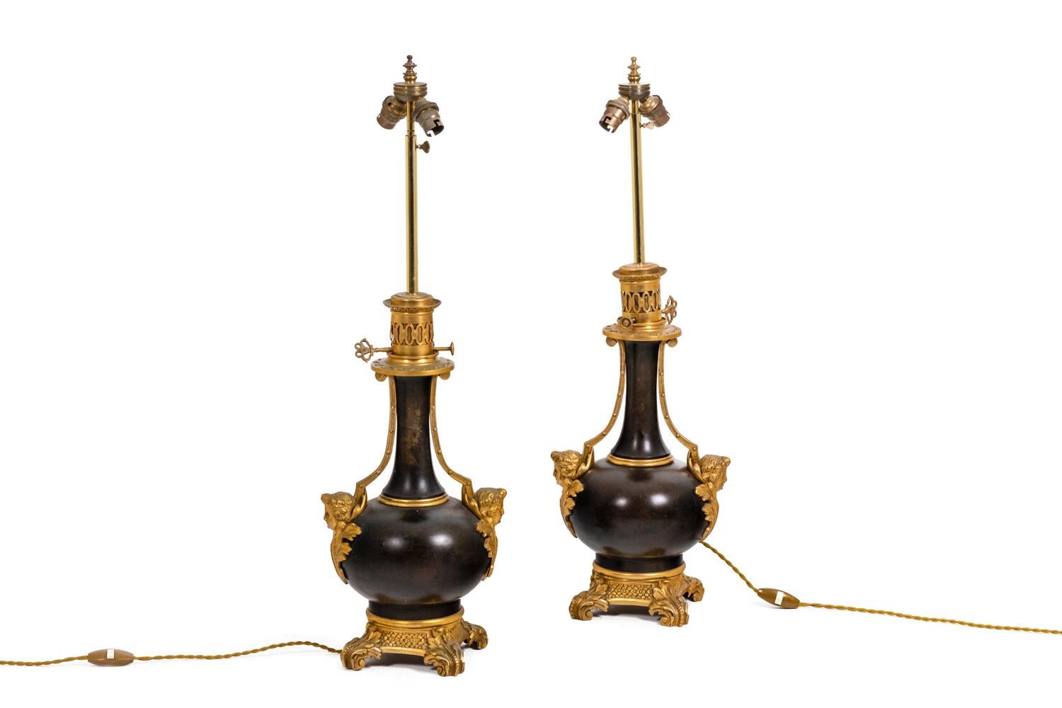 Pair of lamps in plate and gilt bronze of baluster shape of brown green color. Chiseled and gilt bronze mount. Decor of cherubs adorned with acanthus leaves on the neck, on each side of the lamp. Quadripod square base adorned with acanthus leaves.