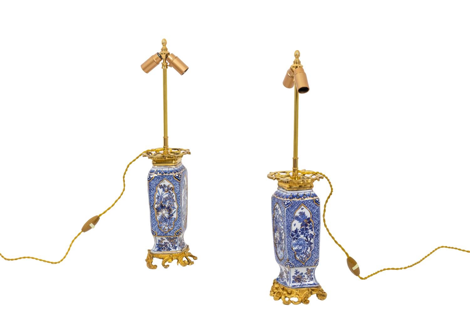 Pair of parallelepiped lamps in blue white porcelain. Decor of gilt cartouche framing flowers like chrysanthemums, cherry blossoms, peonies, etc. on a svastika background on a checkerboard pattern and angles decorated with ruyi. They are framed with