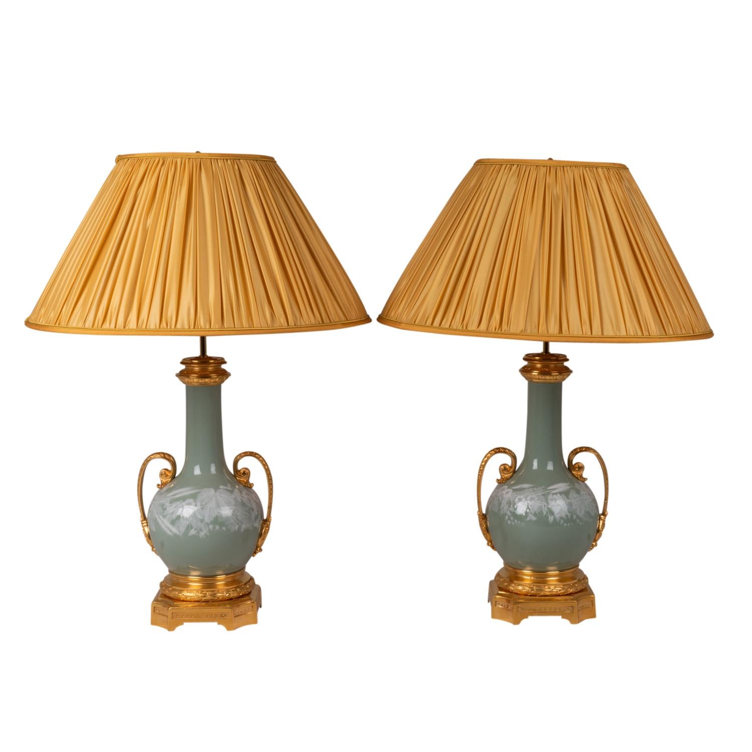 Pair of Celadon porcelain and gilt bronze lamps, adorned with porcelain white flowers, with two handles. Quadripod base with four concave angles.

French work realized circa 1880.

New and functional electrical system. !

The price indicated