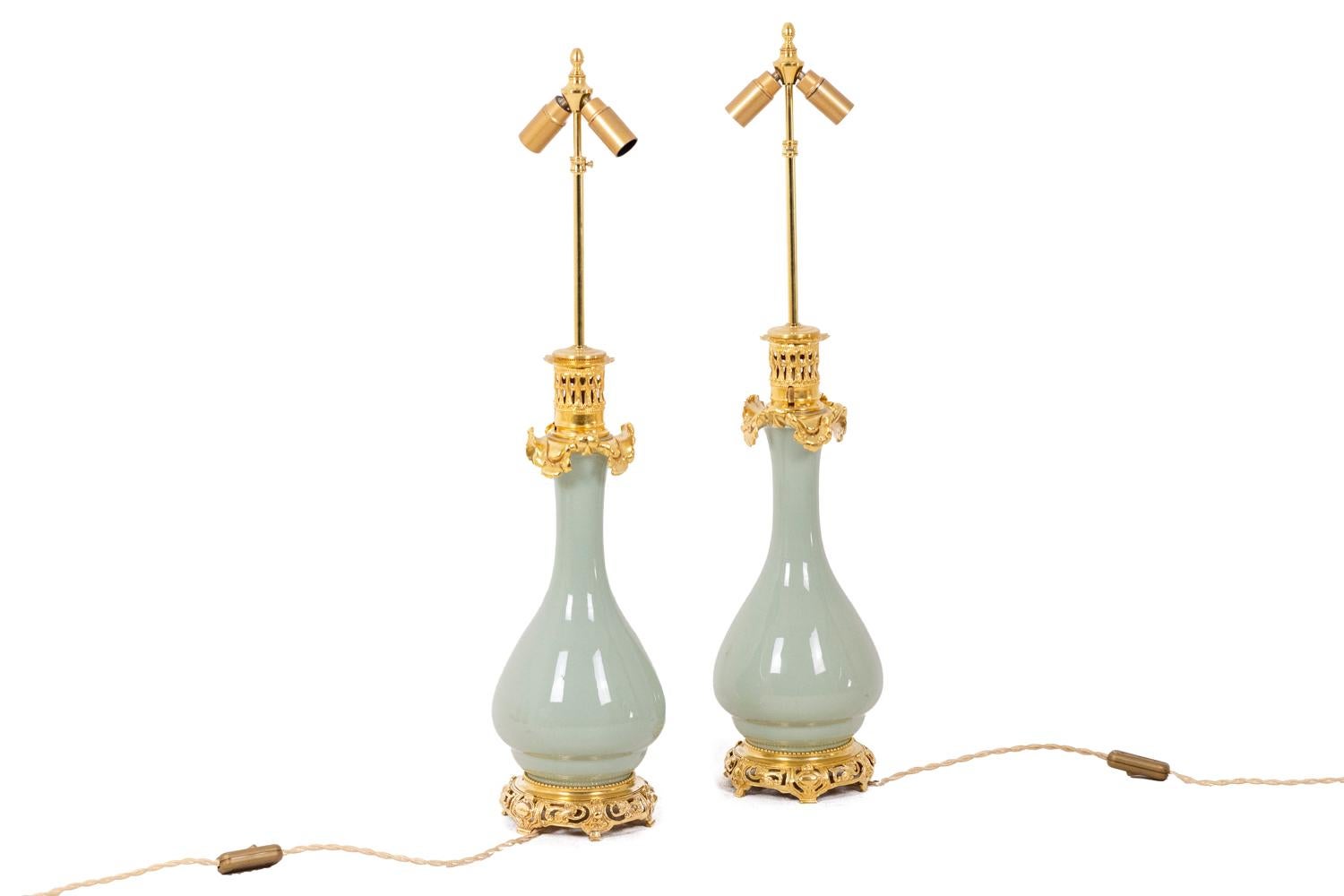 Pair of celadon porcelain lamp, solid color. Gilded and chiseled bronze, the top of the frame presenting an openwork grid and a decoration of wavy leaves. Openwork circular base decorated with scrolls and cartouches, the top of the base decorated