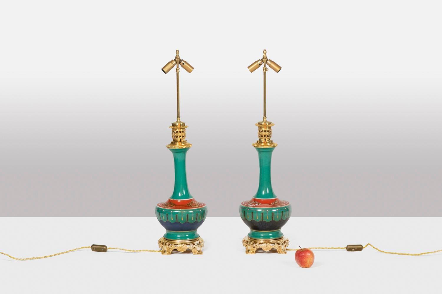 Pair of lamps in Paris porcelain and bronze, baluster shaped and red and green in color, the red part decorated with crests, the green part decorated with scraps of ribbons.
Base and top of the frame in gilded bronze, the openwork base decorated
