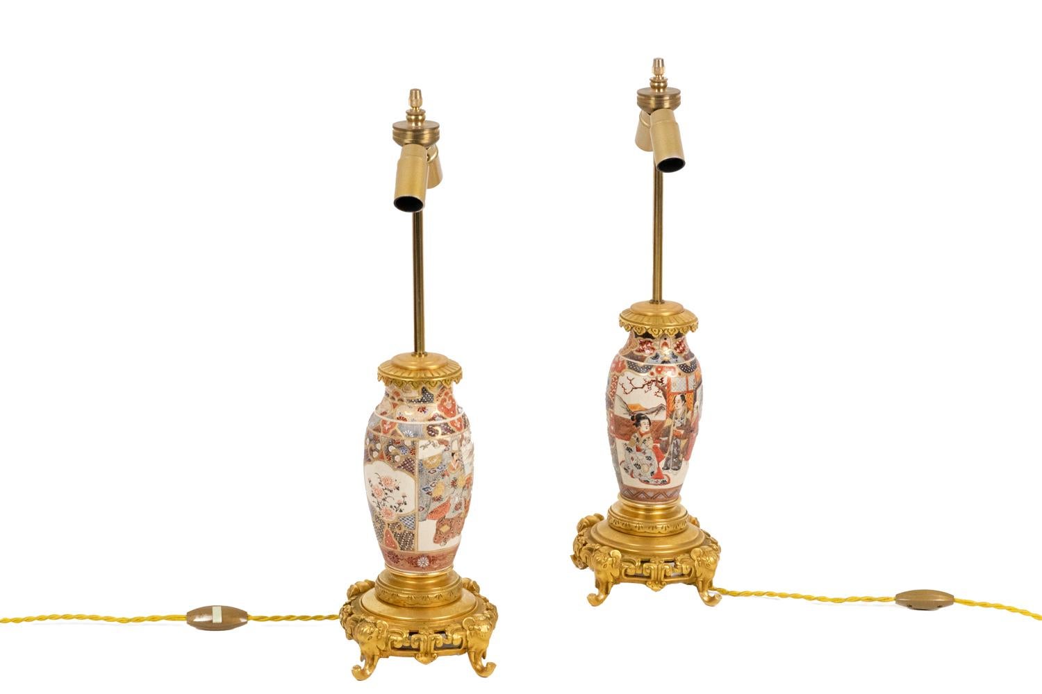 Pair of small baluster shape lamps in Satsuma earthenware decorated with polychrome enamels on a white background.
Decor of palace scenes with many Asian characters on landscape, wall hangings and palace decor and cartouches with flowers decor.