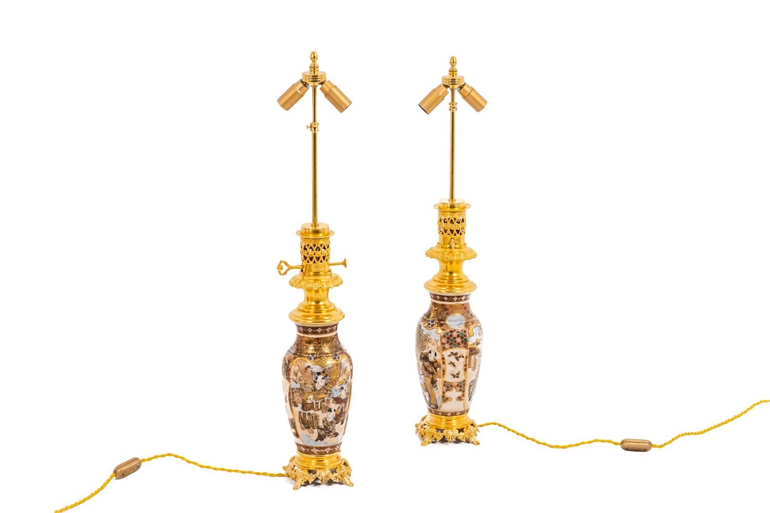 Pair of fine Satsuma earthenware lamps predominantly gold and gilded bronze. Ovoid shape surmounted by a neck in white cartouches on a gold background, adorned with butterflies and children. Openwork and gilded bronzes in an eclectic