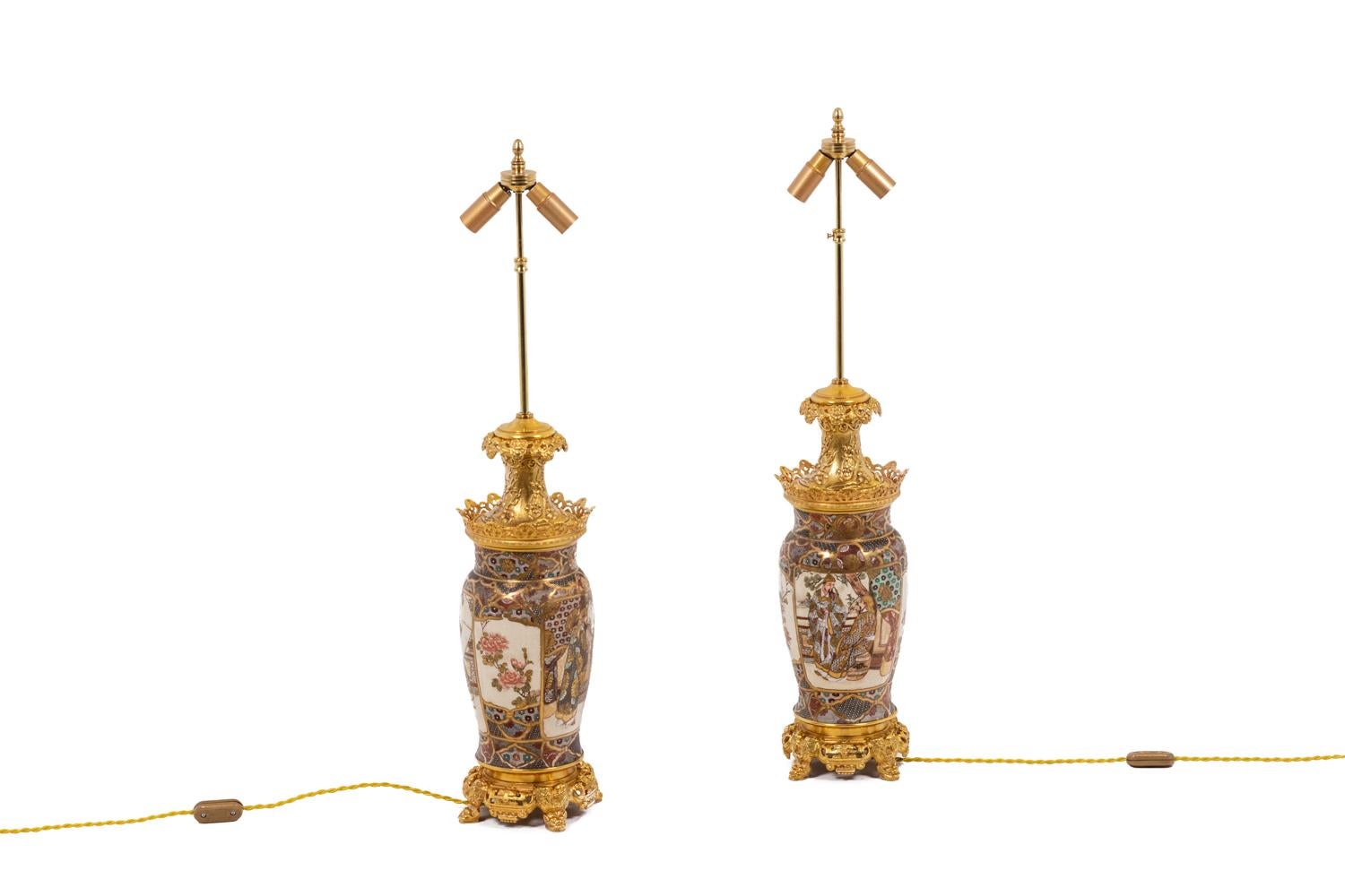 Pair of egg-shaped lamps in a fine Satsuma earthenware. Body presenting Japanese dignitaries speaking together inside cartouches on a white background as well as red, golden, brown and green decorative and geometric motifs. Mount in gilt bronze