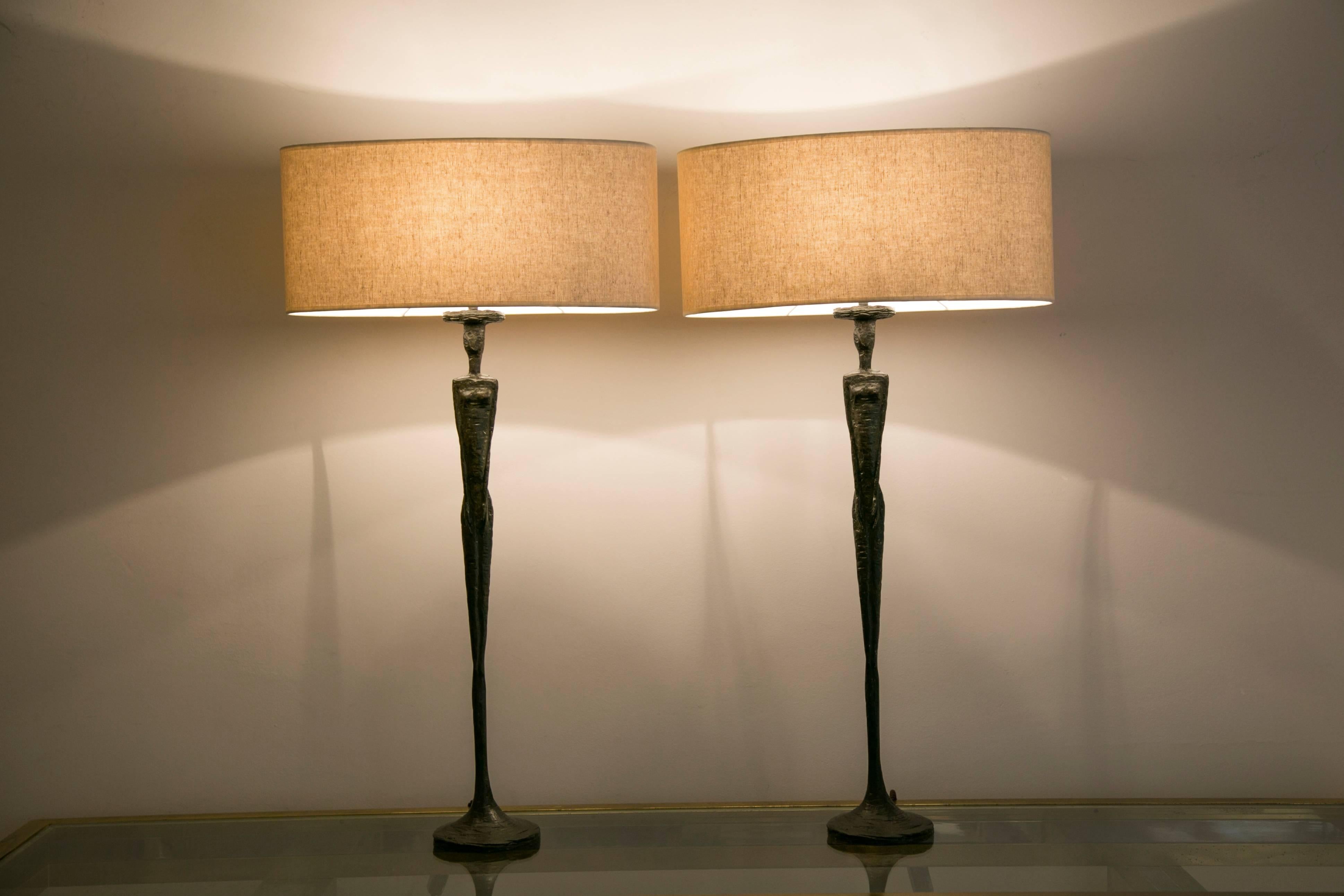 A pair of cast composite lamps with bronze patina, figuring tall human figures.
New shades
Marked: PR for Porta Romana
England, 1990s
Provenance: Hôtel Martinez, Cannes, France

Dimensions: 
Height (total) 85.5 cm / 33.46 in.
Height (figure)