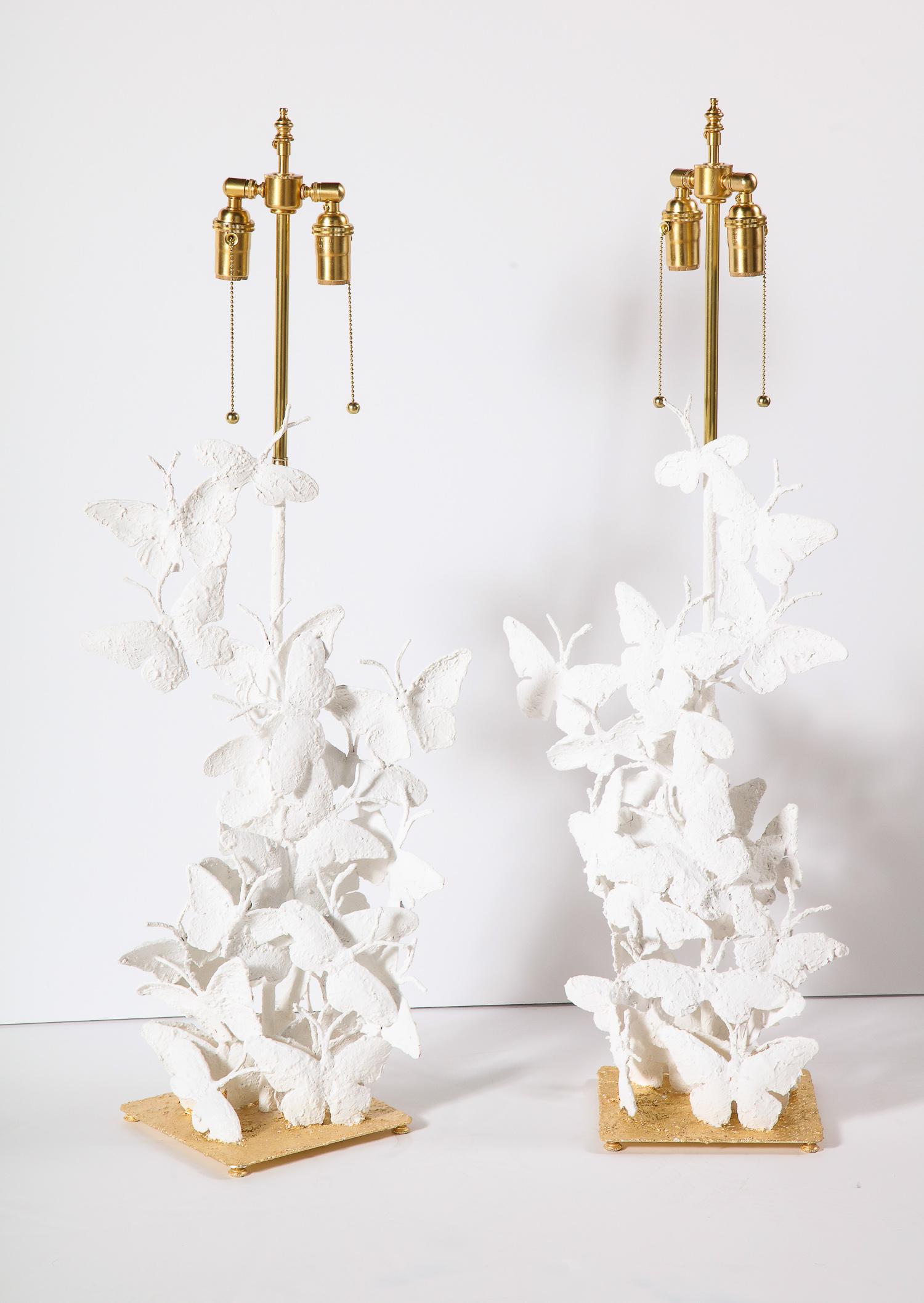 Decorative pair of table lamps with an ocean of butterflies. The lamps are made of metal with design of plaster. Base is covered in gold leaf. Brass lamp parts.
