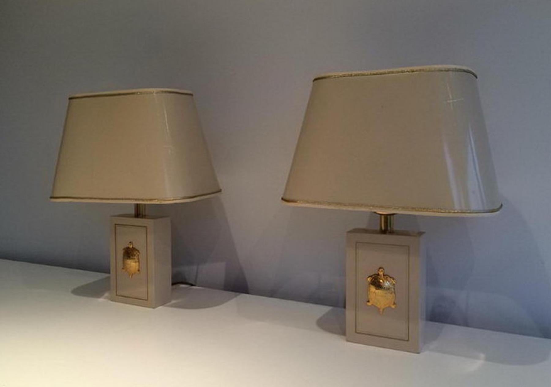 This pair of table lamps are made of a white lacqued wood with gilt turtles ornaments. This is a French work, circa 1970.