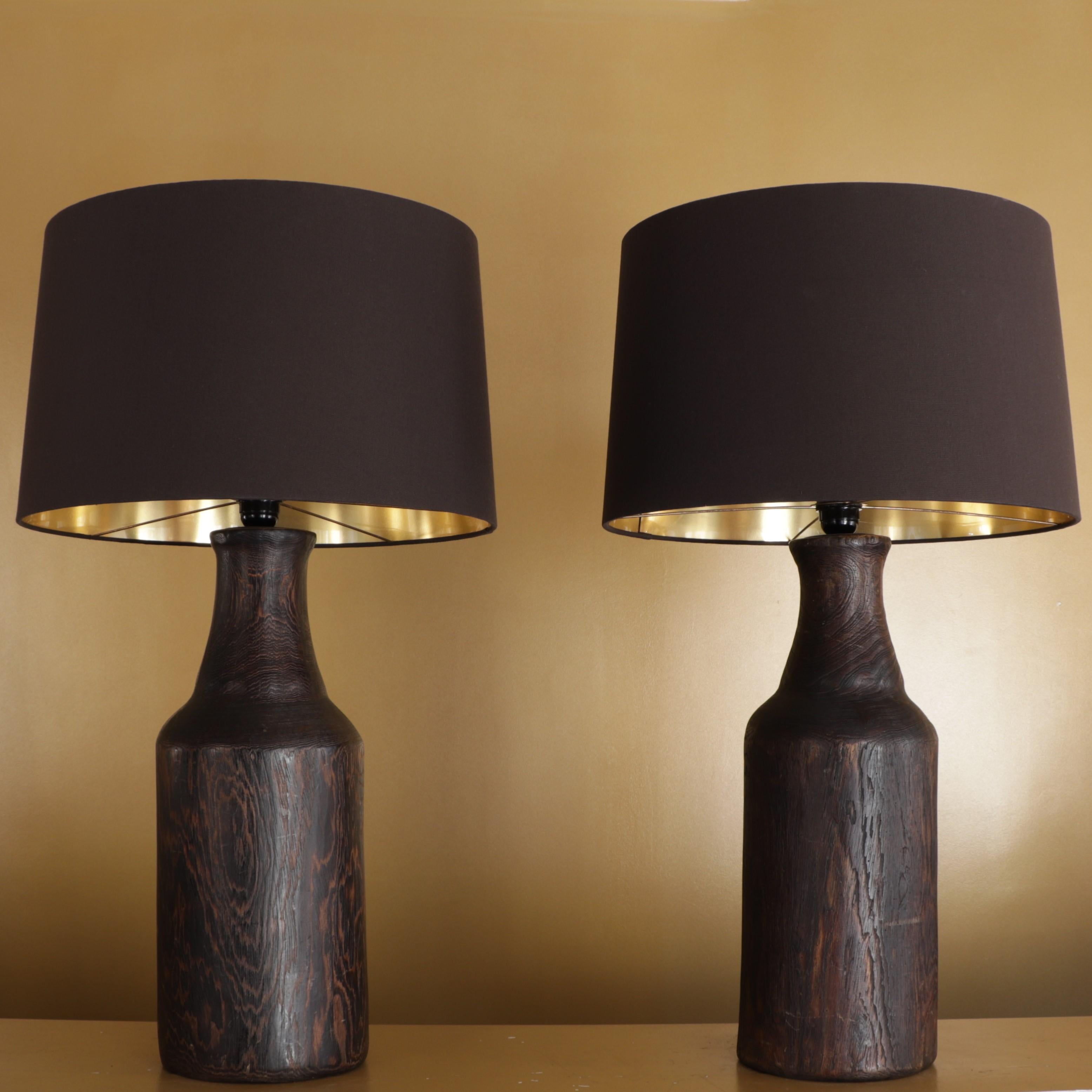 Pair of lamps composed of large dark wood foot and a dark brown lampshade with gilded interior.