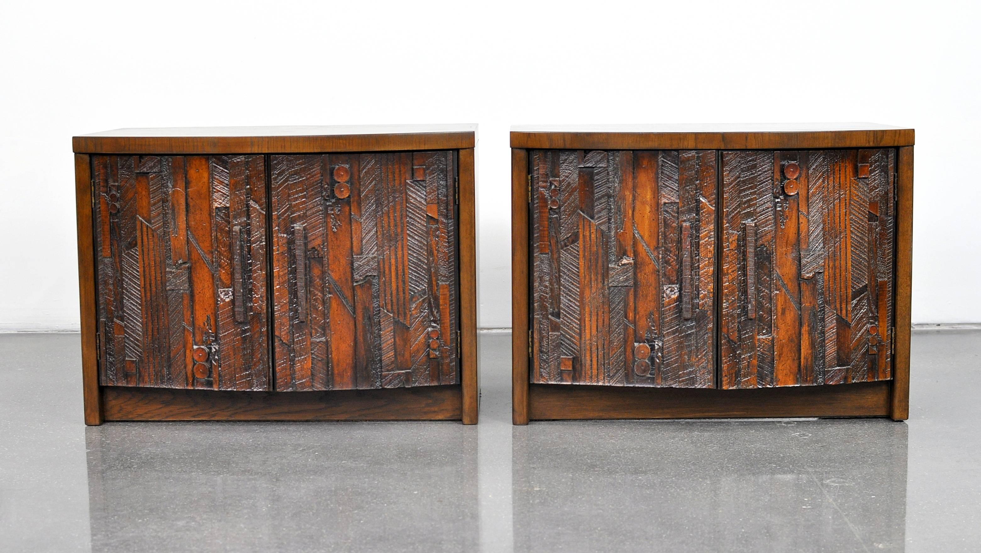 Bold and sculptural pair of Mid-Century Modern vintage side tables manufactured by Lane in the 1960s. The cabinets feature shaped doors with Paul Evans style or Cubist mosaic style patchwork, opening to an interior fitted with a shelf. Striking