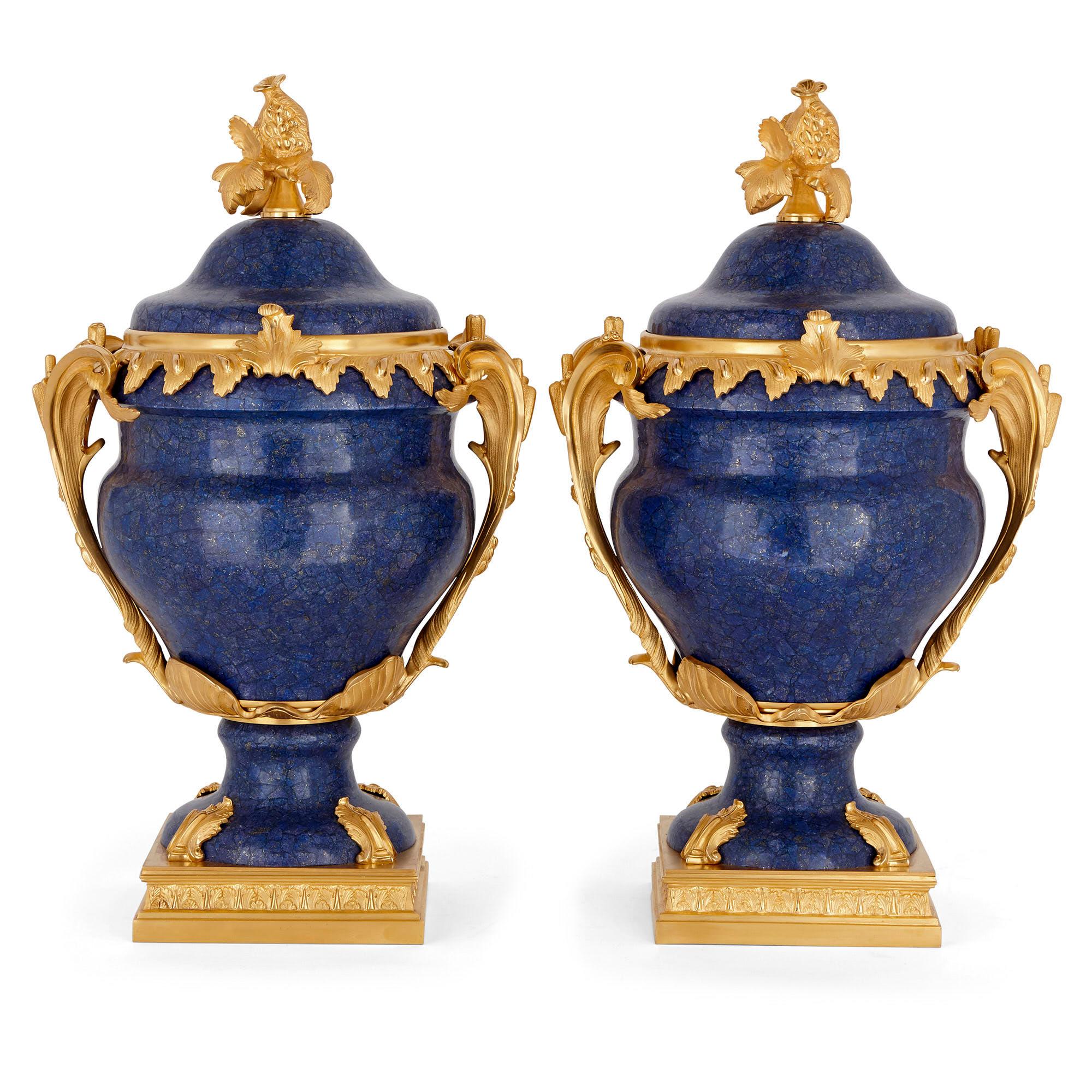 Each krater form vase in this pair is made of gilt bronze mounted lapis lazuli. The vases stand on square gilt bronze bases which attach to the feet of the vases with acanthus leaf gilt bronze mounts. From a gilt bronze band around the top of each