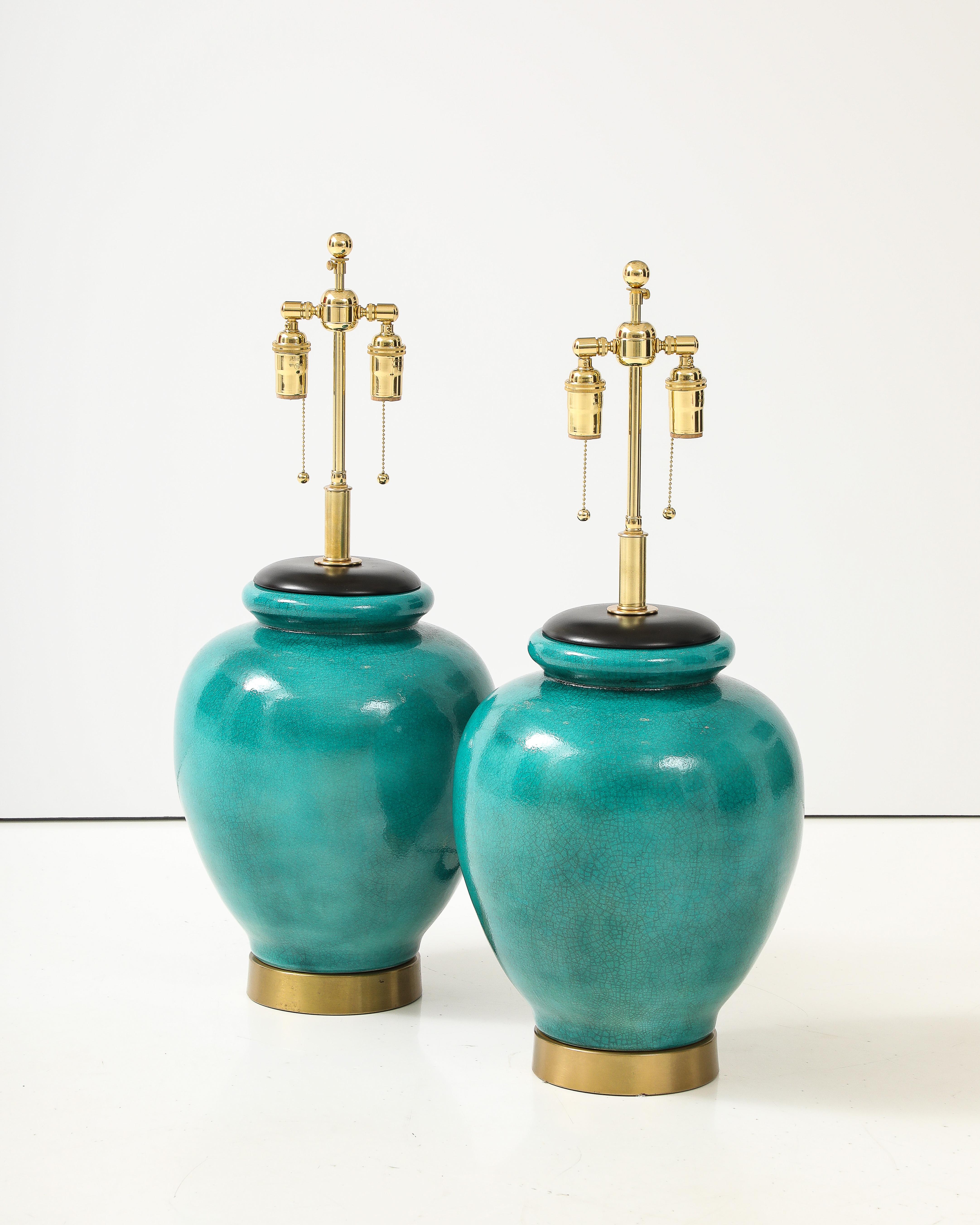 Merveilleuse paire de lampes en céramique des années 1950 avec une belle glaçure craquelée.
Les lampes reposent sur des socles en laiton et ont été nouvellement câblées avec des câbles réglables. 
doubles grappes en laiton poli et cordes en rayonne