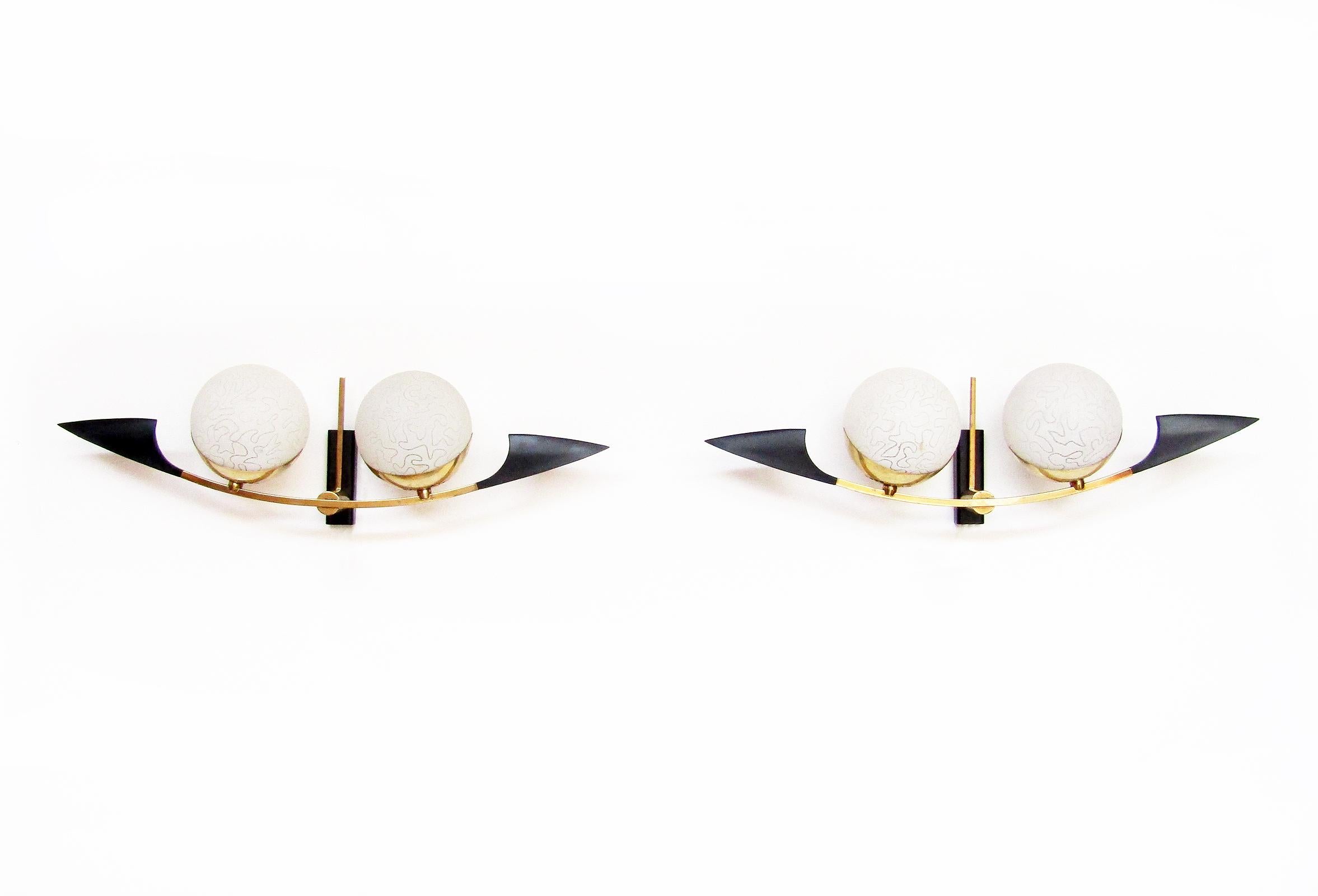 A pair of elegant globe wall sconces by French makers Maison Arlus, circa 1960.

The original globe shades are made from opaque matt glass with organic etched design. They are held on stylized brass arms with brass holders. They are 58cm in