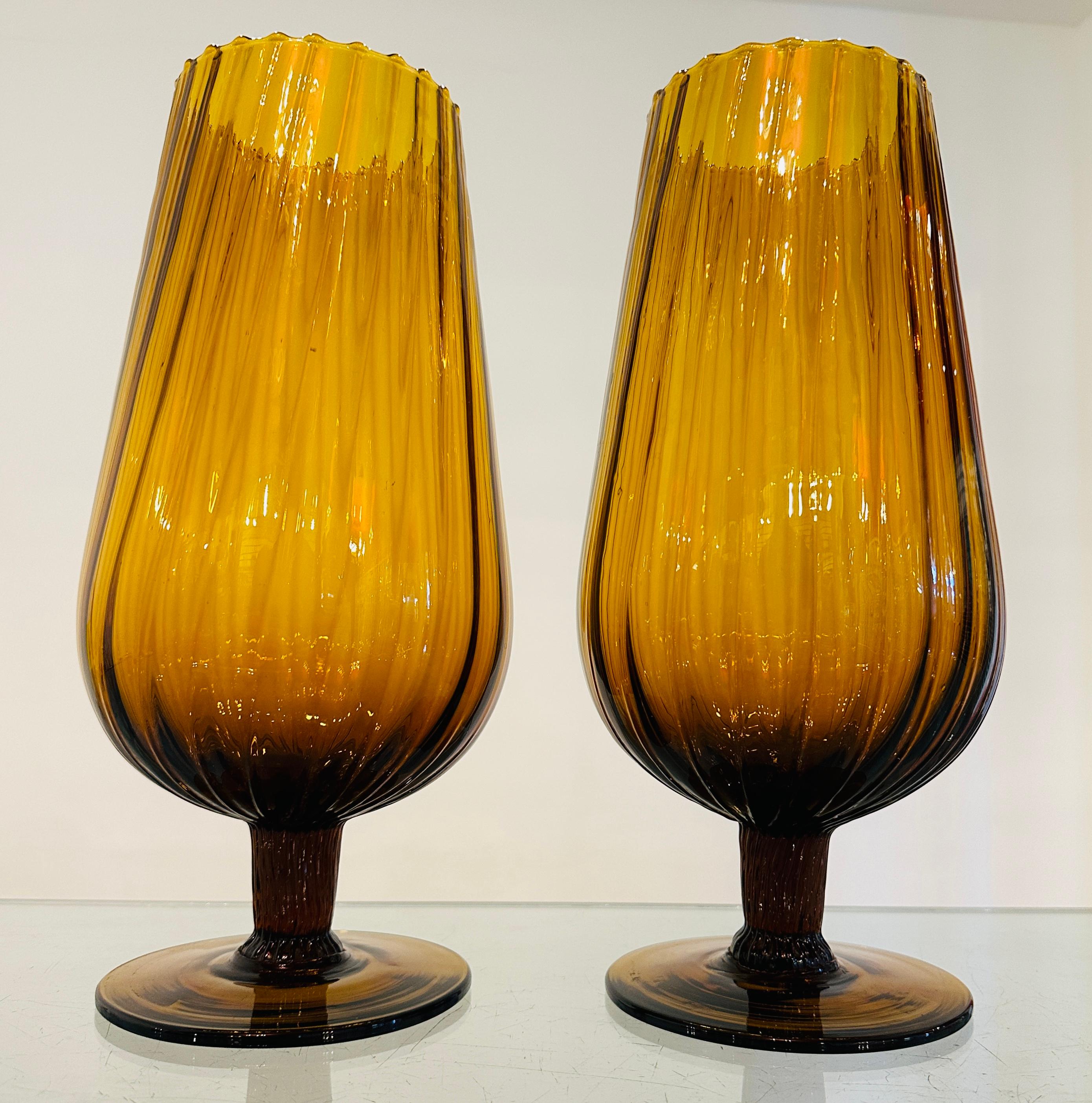 Pair of large vintage 1960s amber coloured swirled and ribbed glass goblet-shaped vases with scalloped rims.  The circular bases are made from a thicker glass to help support the vase and are a darker amber colour. The ribs in each stem extend
