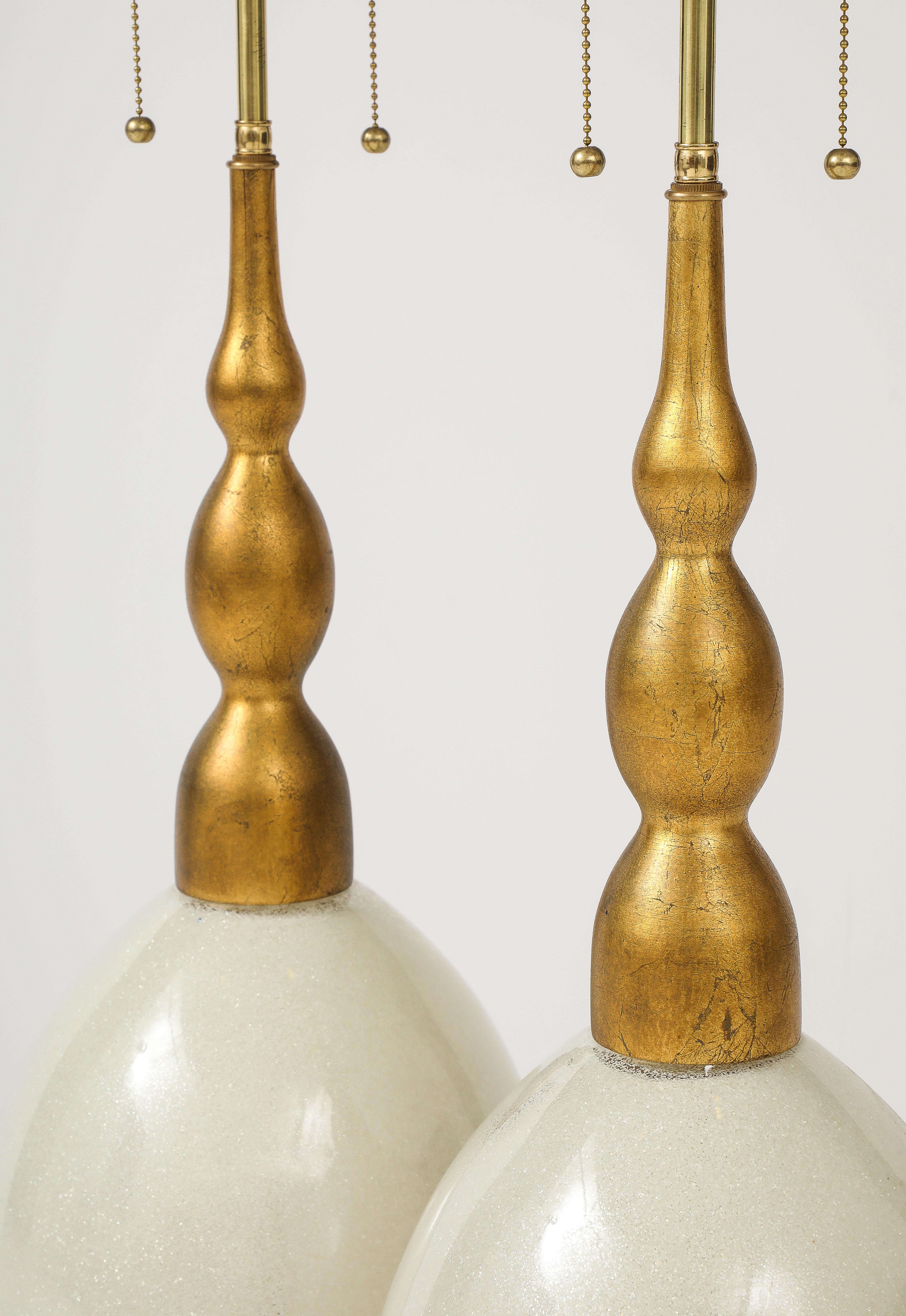 Paire de lampes en verre Murano de Marble Lamp company.
La grande mouchetée  Le verre de Murano, en forme d'œuf, est joliment irisé et se pose sur des pieds de lampe dorés 
Les lampes ont été refaites à neuf avec des doubles grappes réglables en