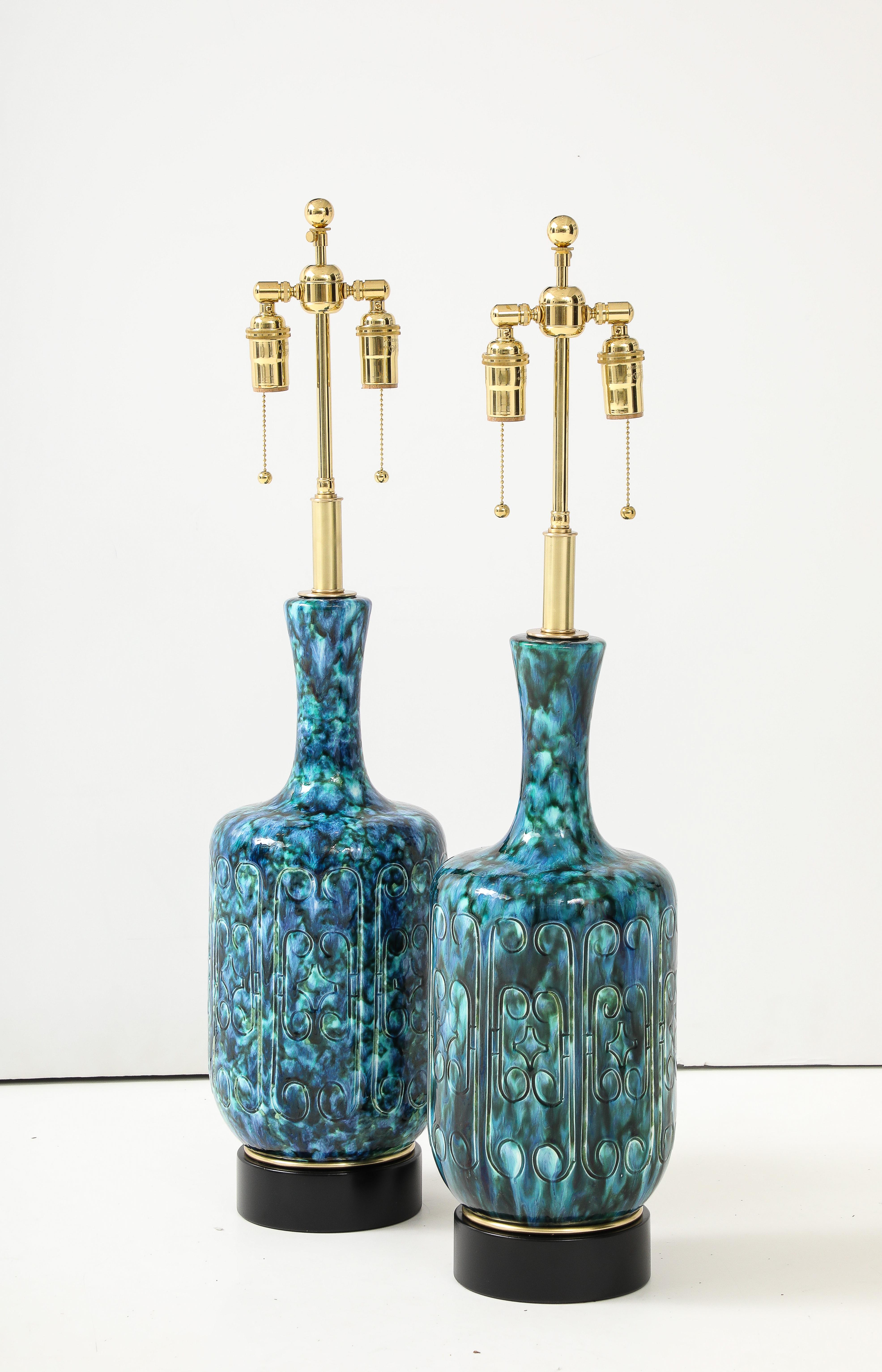1970's Paire de grandes lampes italiennes en céramique avec une  magnifique glaçure bleue tachetée  
et une incision décorative  modèle de conception.
Les corps des lampes en céramique reposent sur des bases noires avec des accessoires en laiton.
