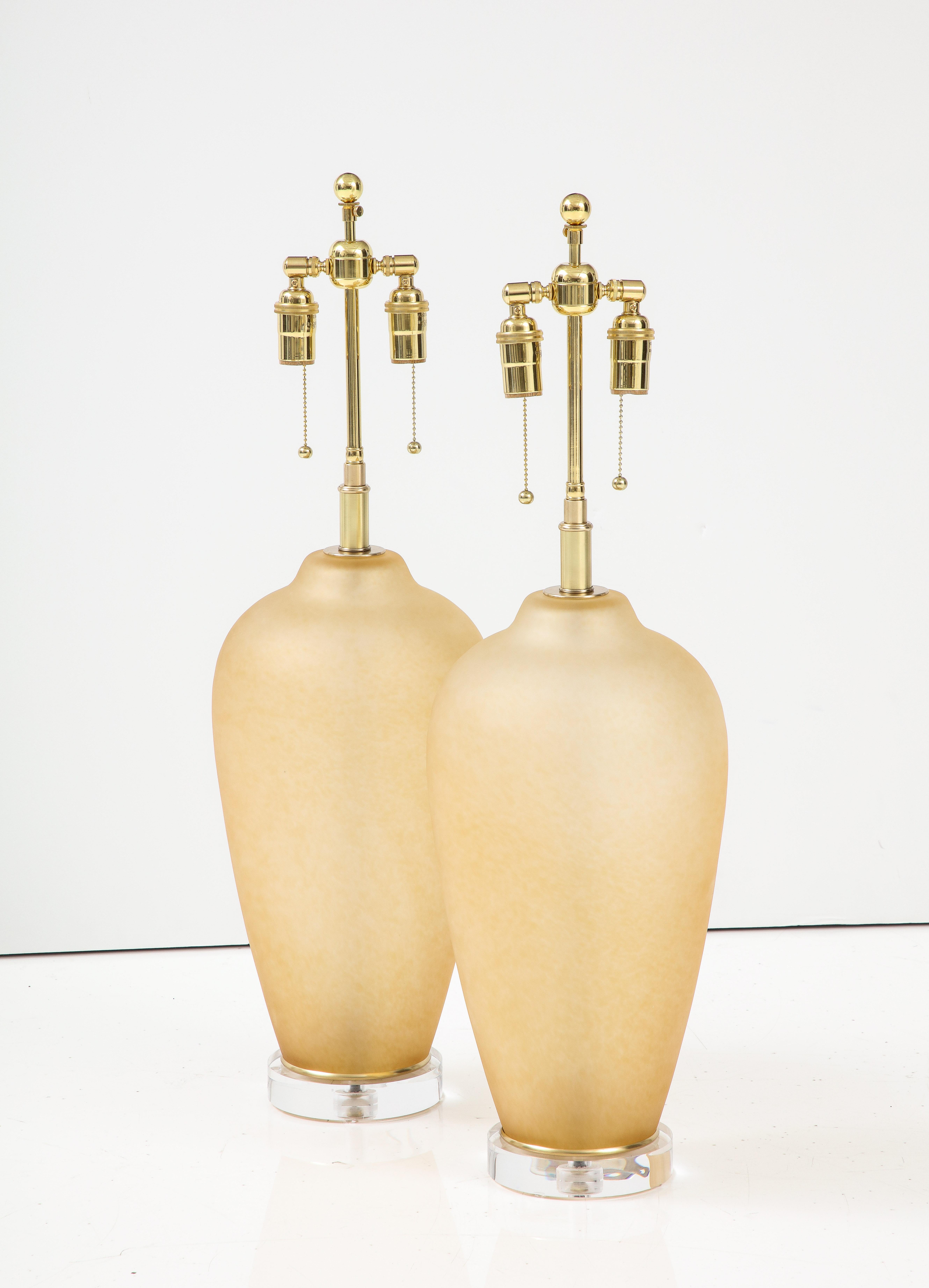 Pair of large Murano glass lamps in a soft Amber color, that are mounted on 
thick lucite bases.
The lamps have been Newly rewired with adjustable polished brass double clusters that take standard size light bulbs.
The height to the top of the glass