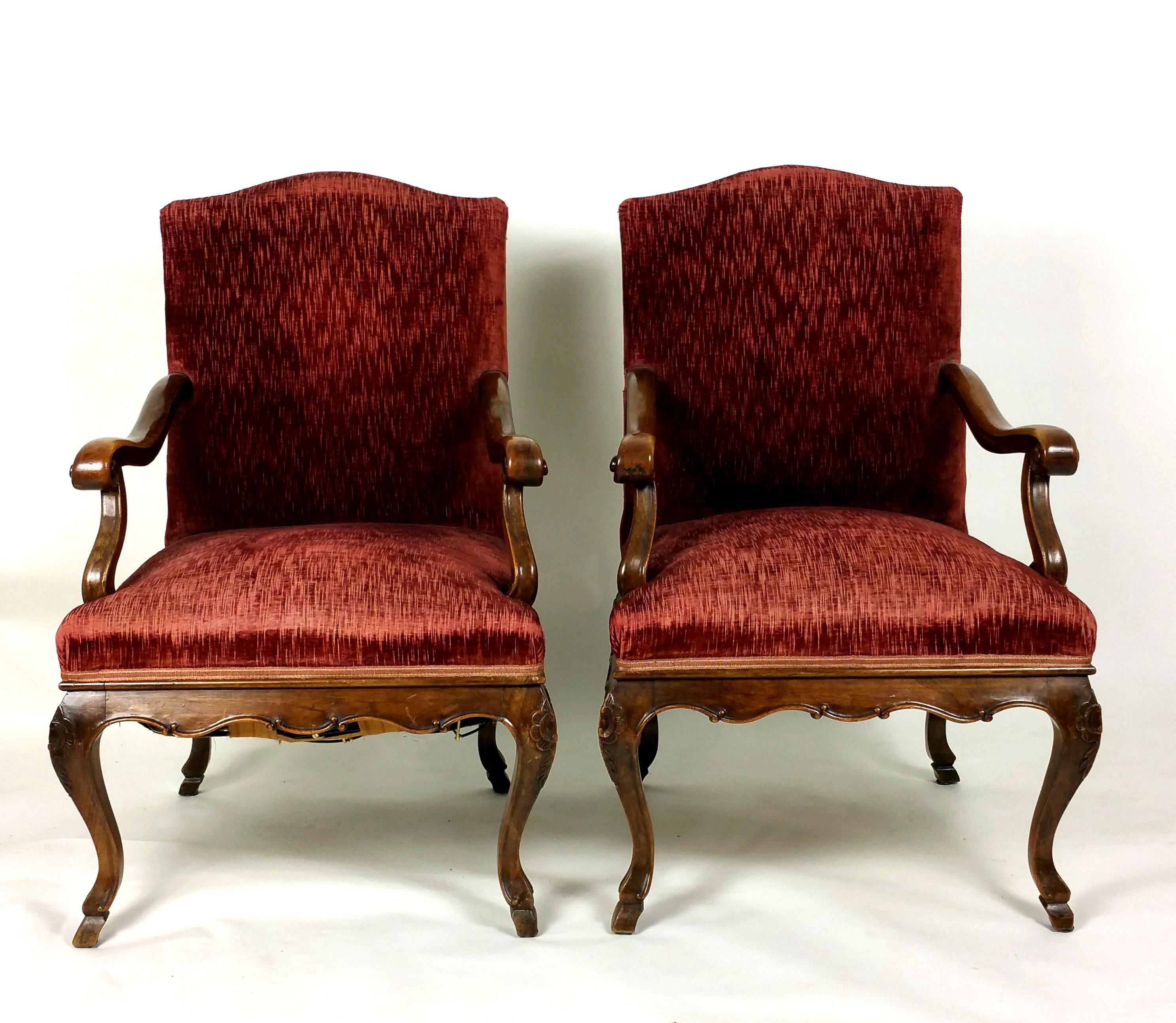 These beautiful large French solid walnut elbow chairs have shaped and scrolled arms, a carved frieze and stand on carved cabriole legs with hoof feet. The back and seat are upholstered in deep red velvet woven fabric. Each chair measures 25 ¼ in –